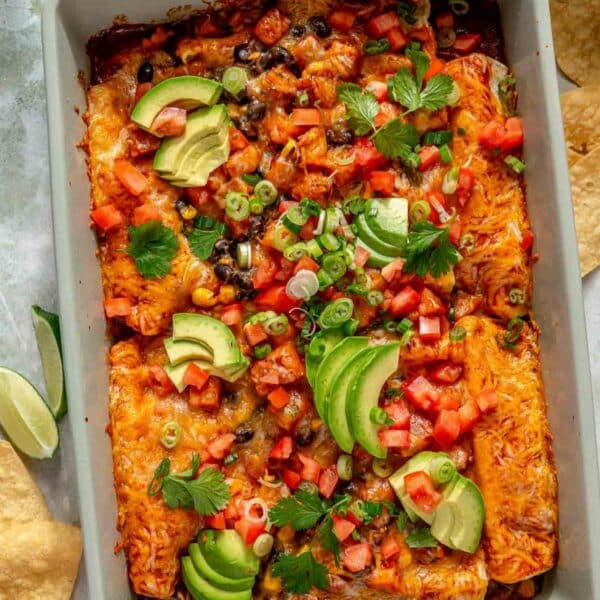 Sweet potato black bean enchiladas topped with avocado slices, green onions and diced tomatoes.