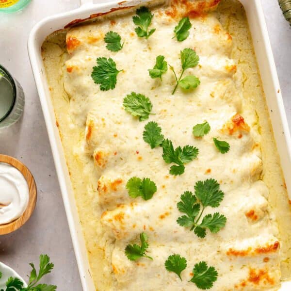 Enchiladas verdes cooked in a white casserole dish and garnished with fresh cilantro.