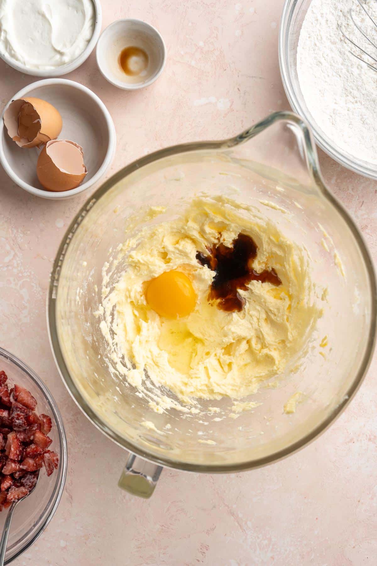 Egg and vanilla added to butter and sugar mixture in a bowl.