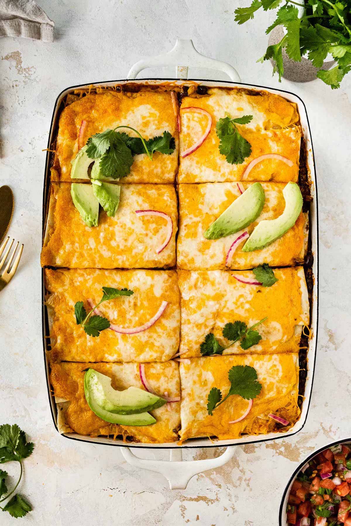 Baked mexican lasagna garnished with avocado and cilantro.