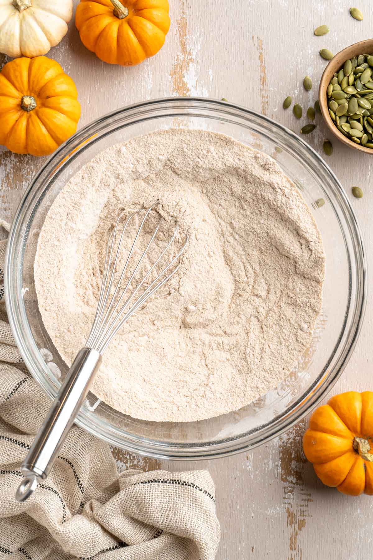 Whisking together flour, flaxseed, sugar and pumpkin pie spice in a large bowl.