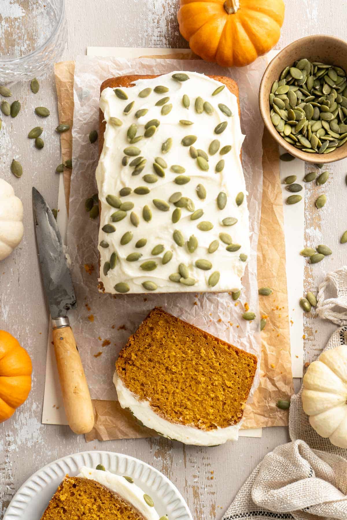 Vegan pumpkin bread topped with vegan cream cheese frosting and pumpkin seeds.