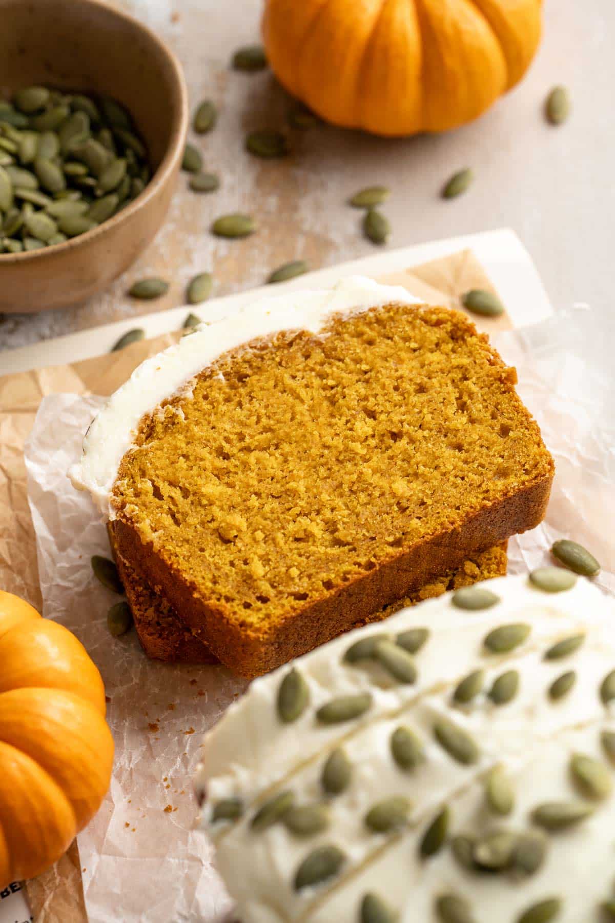 Slice of vegan pumpkin bread scattered with pumpkin seeds.