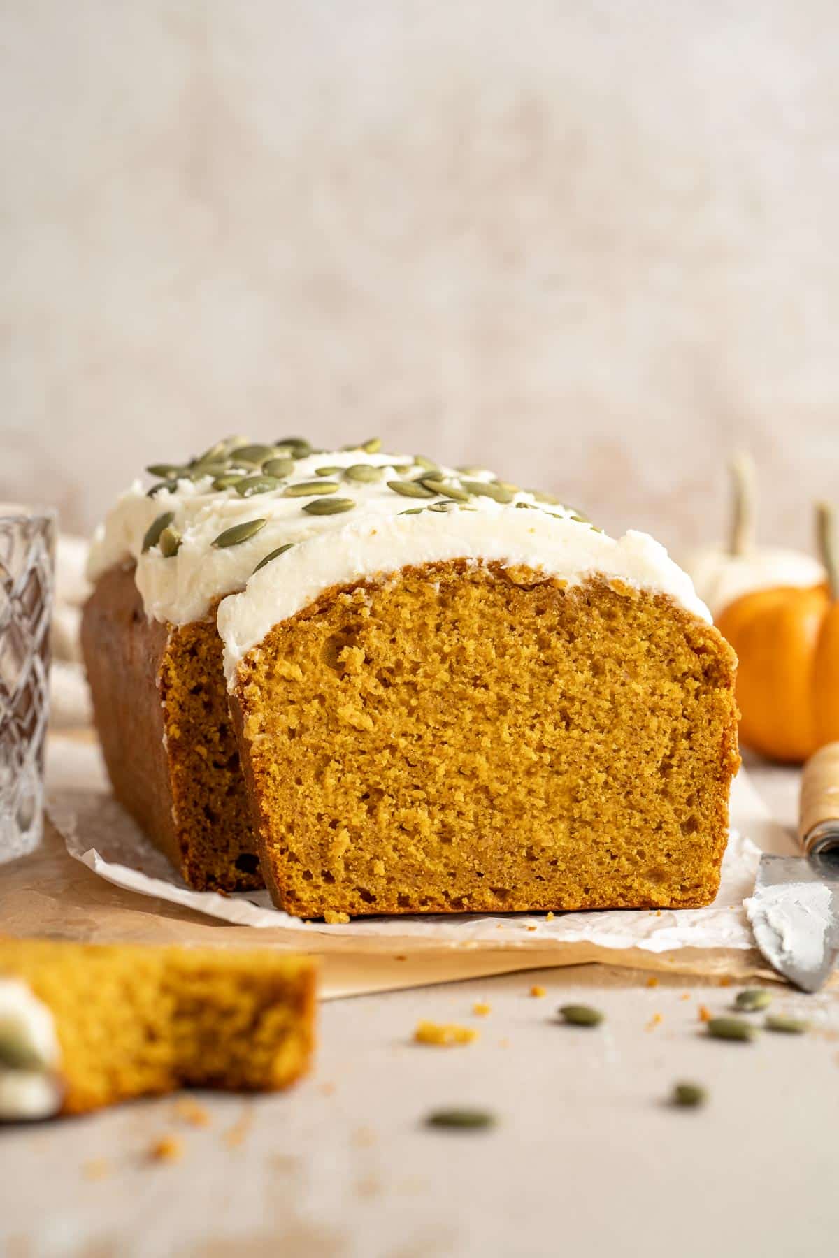 A sliced loaf of vegan pumpkin bread with cream cheese frosting.