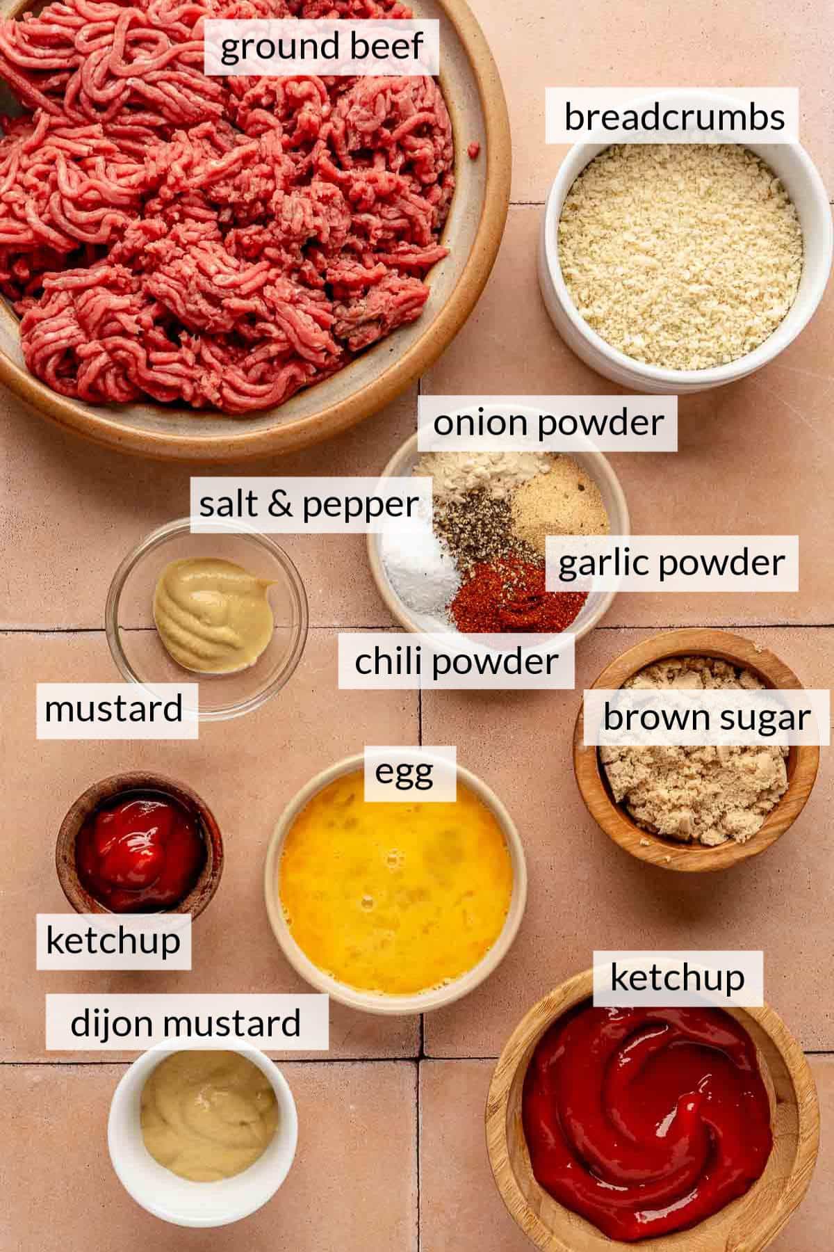 Ground beef in a bowl near breadcrumbs, spices, beaten egg, brown sugar, ketchup and mustard.