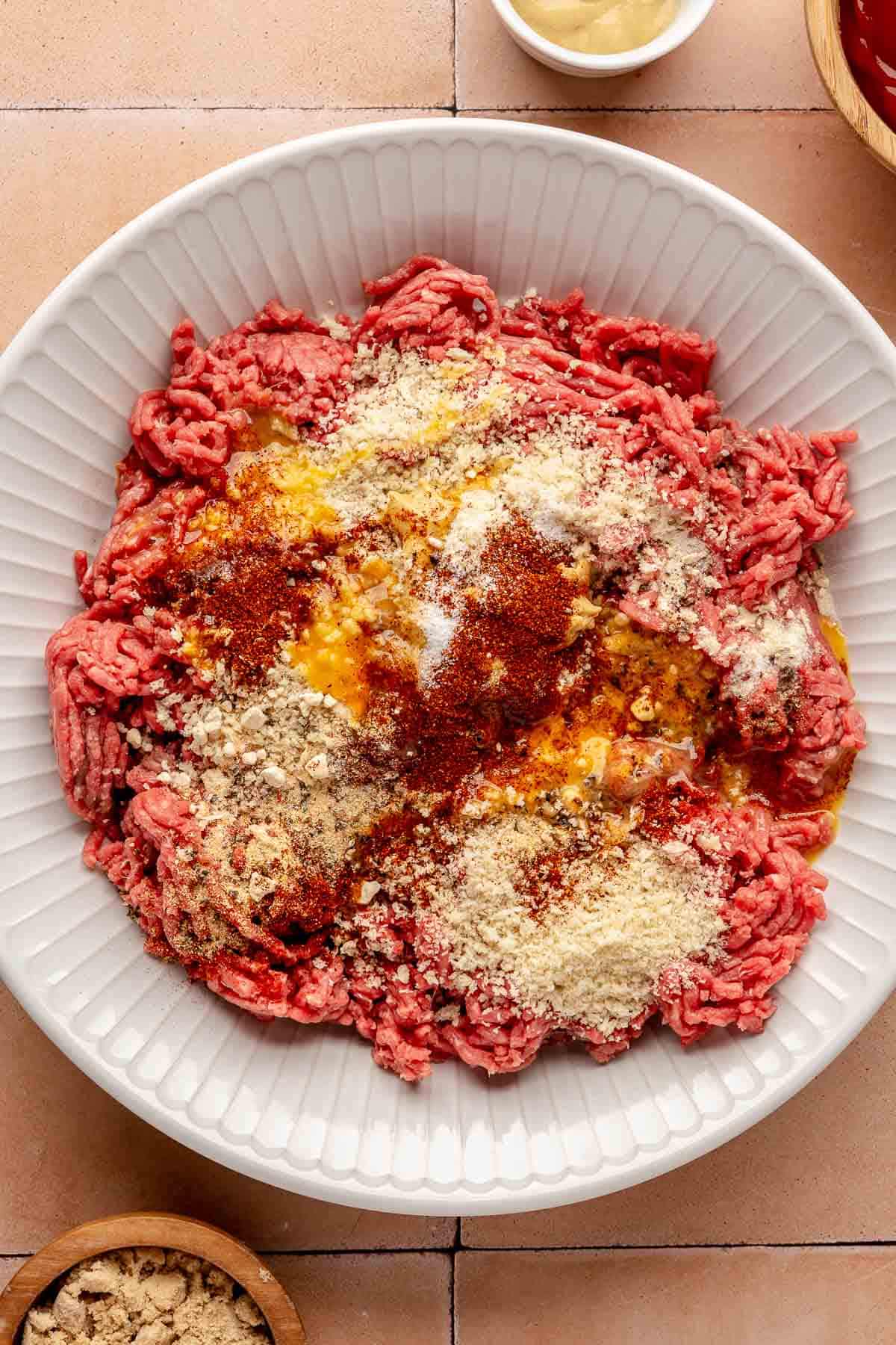 Ground beef in a bowl topped with seasonings.