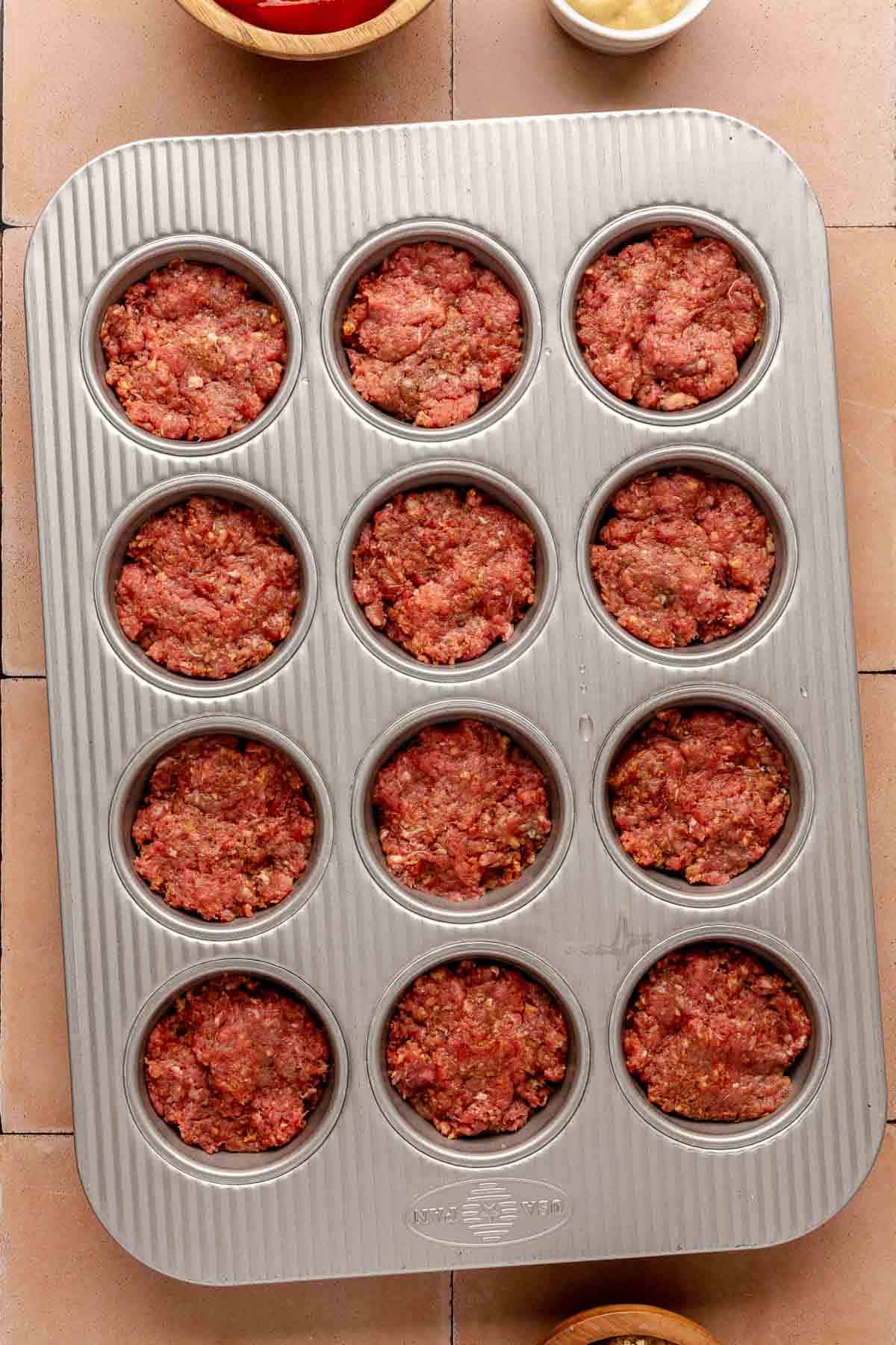 Meat mixture divided into a muffin pan.