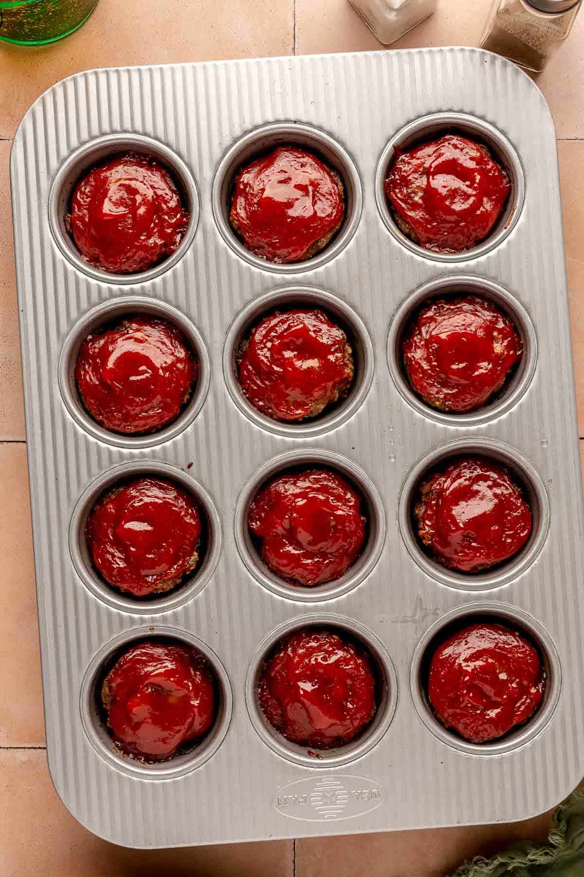 Glazed mini meatloaves in a muffin tin.