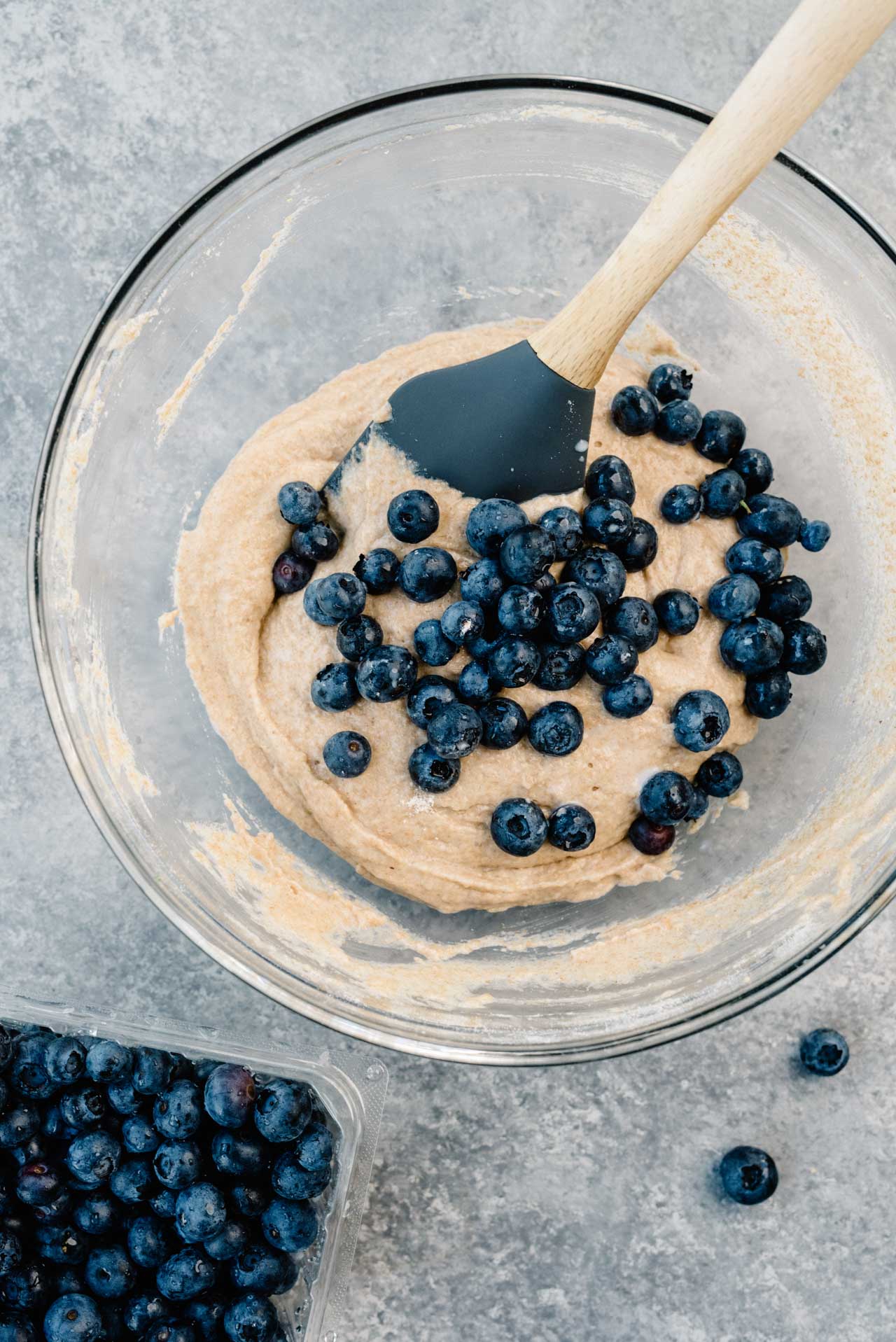 batter for baked blueberry donuts in a glass mixing bowl with spoon