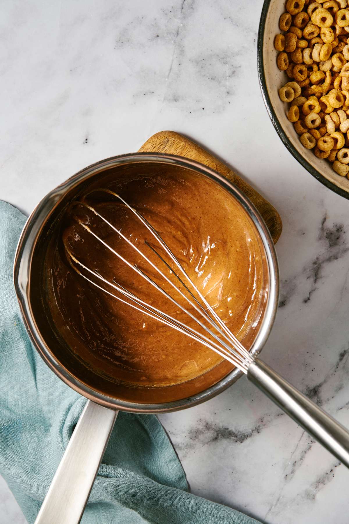 Using a whisk to stir honey with almond butter in a pot.