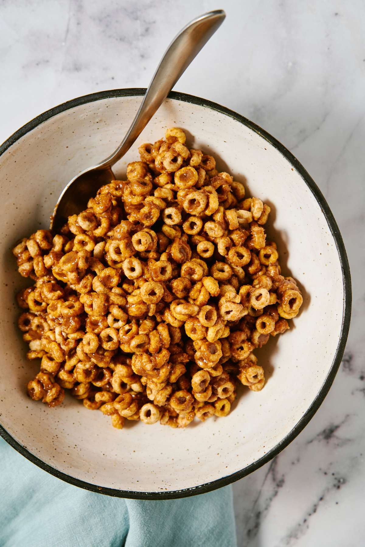 Stirring honey/almond butter mixture with Cheerios in a bowl.