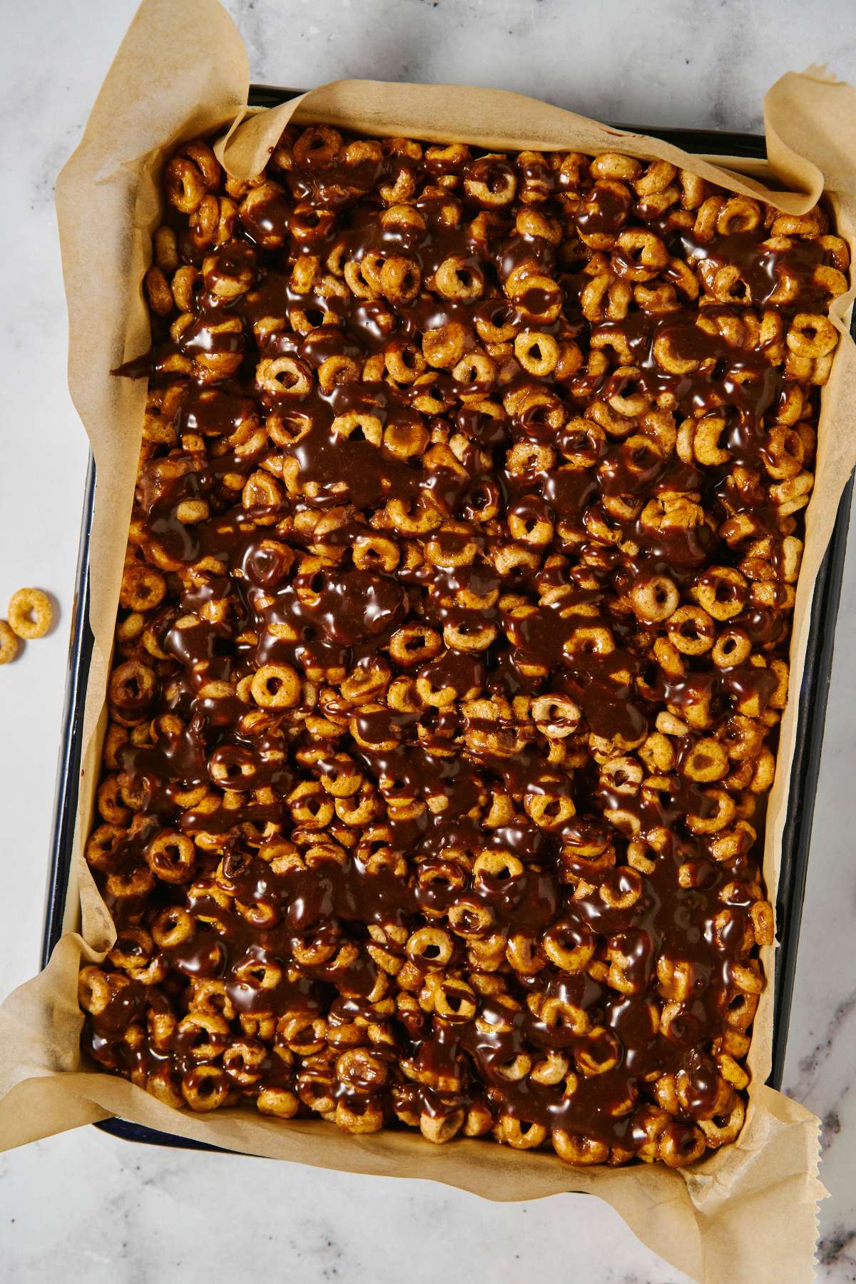 Chocolate drizzled over cereal bars in a pan.