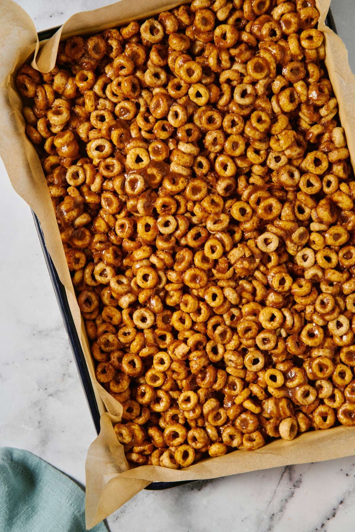 Cheerios mixture pressed into a pan lined with parchment paper.