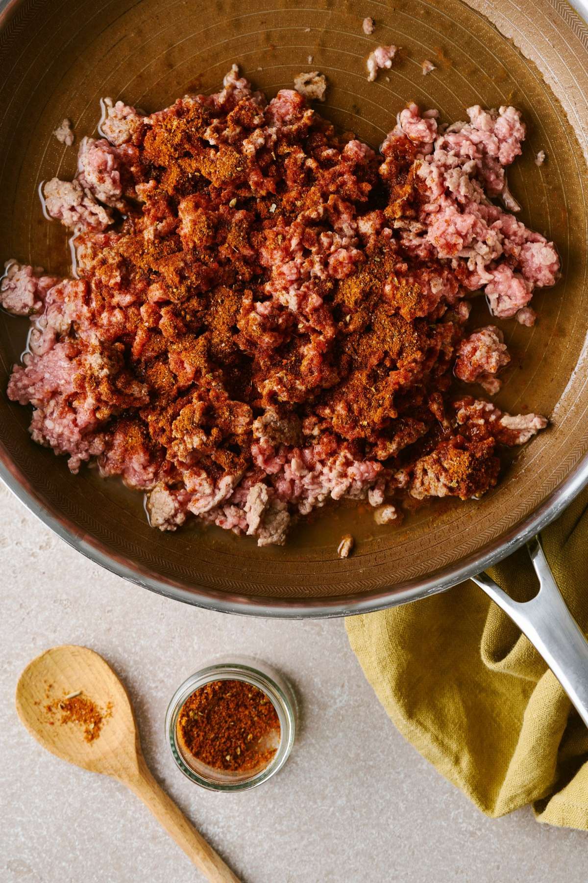 Taco seasoning sprinkled over ground meat in a pan.