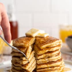 A stack of pancakes being cut into with a fork.