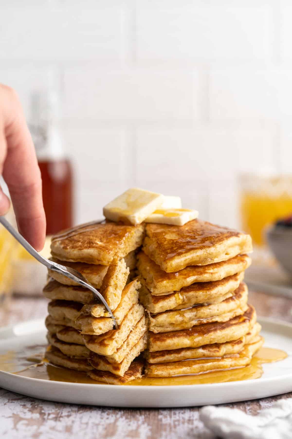 A stack of pancakes being cut into with a fork.