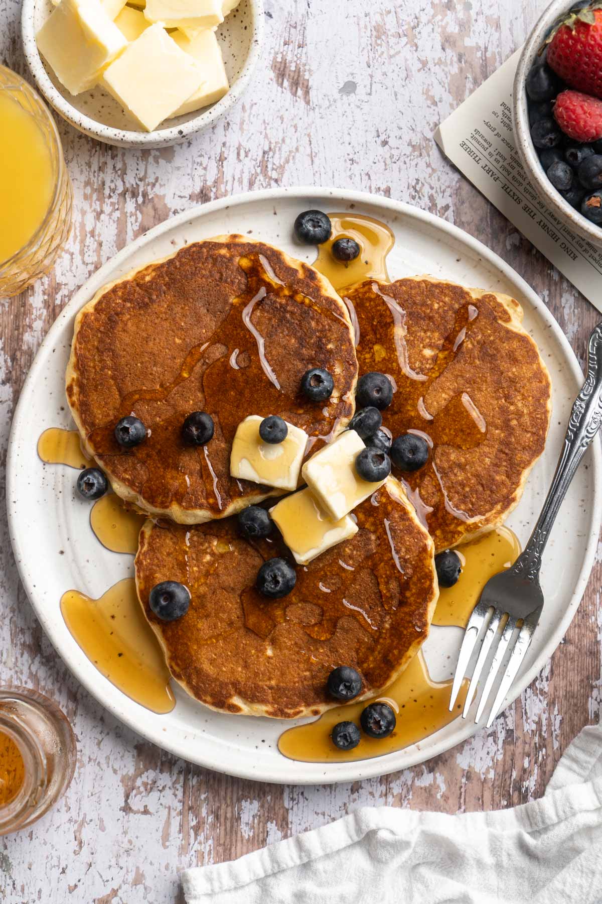 Whole grain pancakes topped with butter, blueberries and maple syrup.