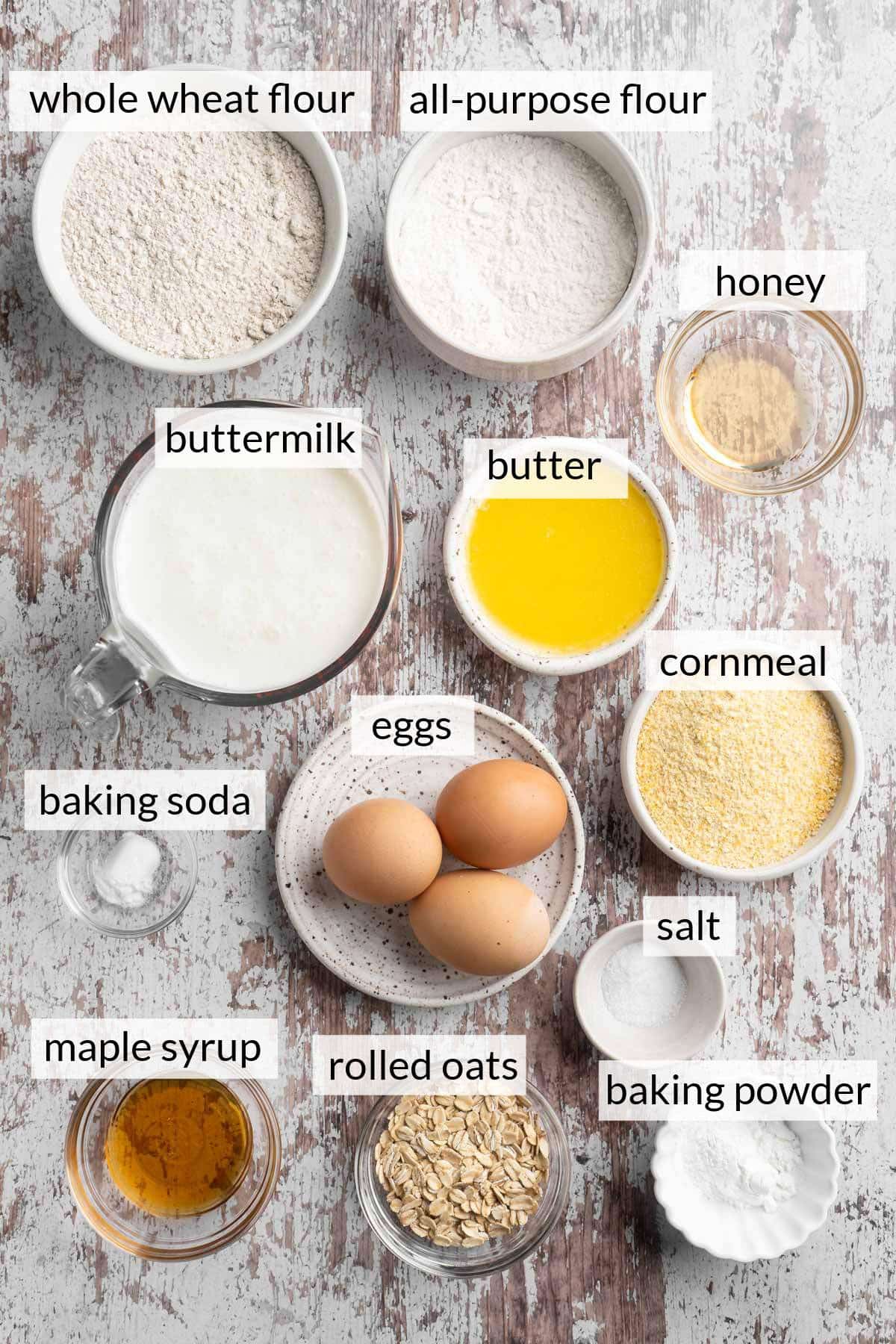 Small bowls with flour, cornmeal, eggs, melted butter, maple syrup and baking powder.