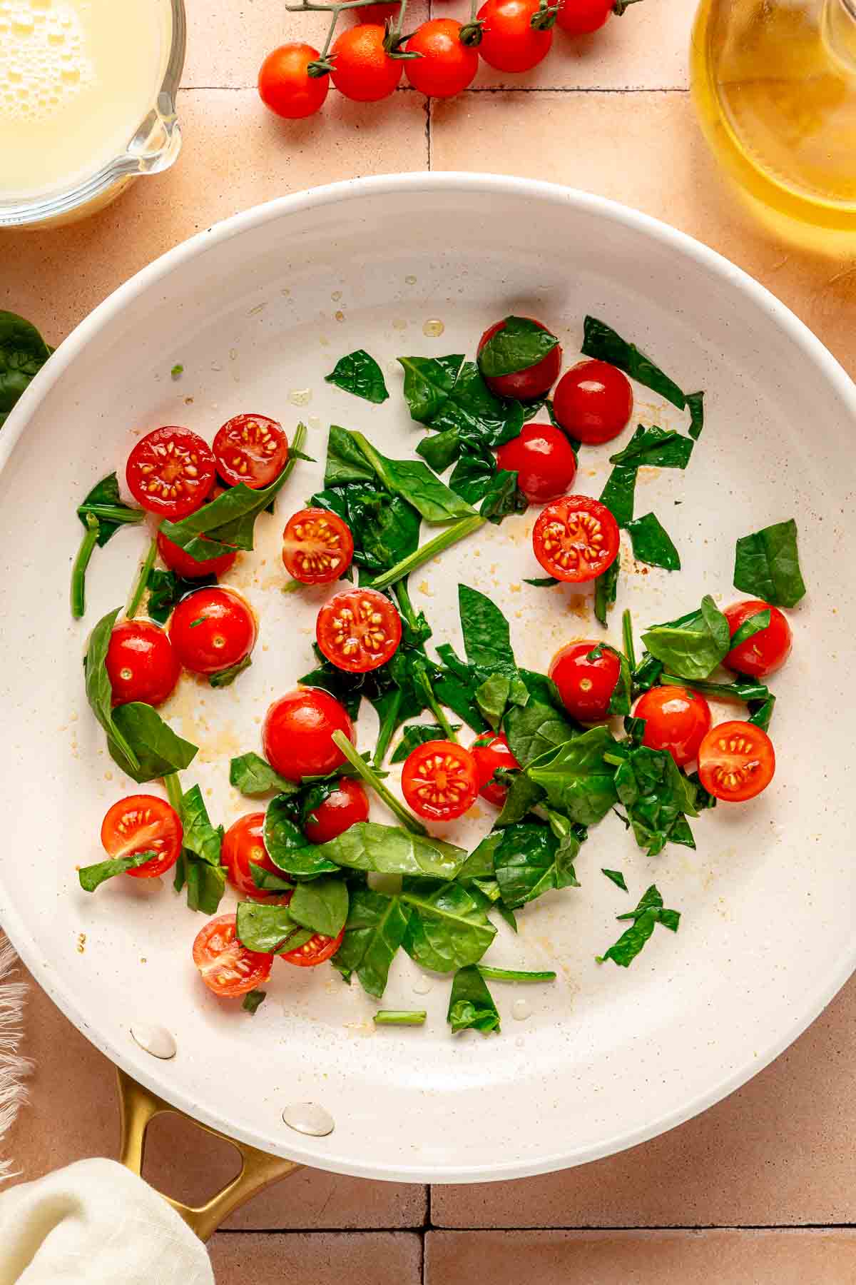 Tomatoes and spinach cooking in a pan.