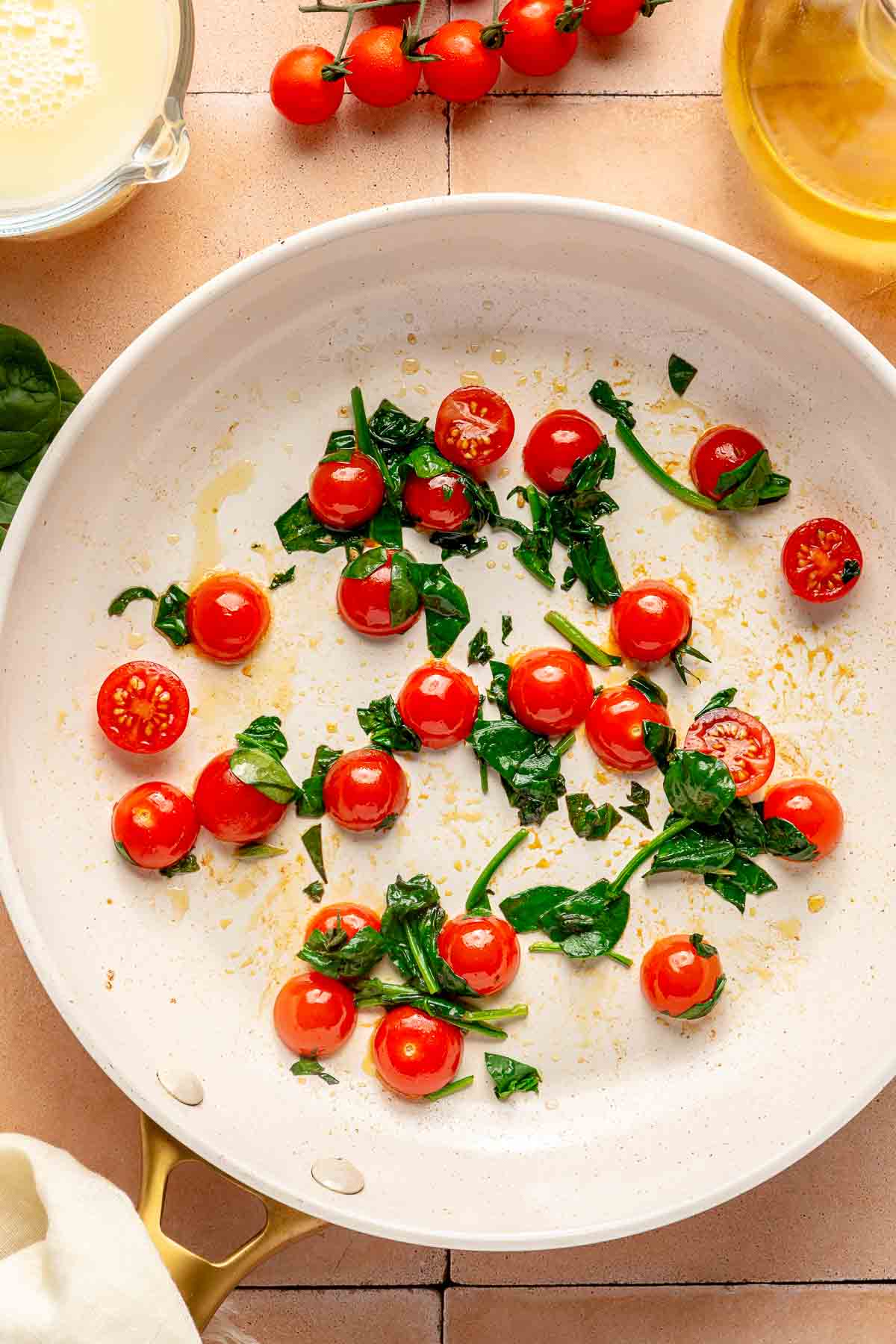 Cherry tomatoes cooking in a large skillet.