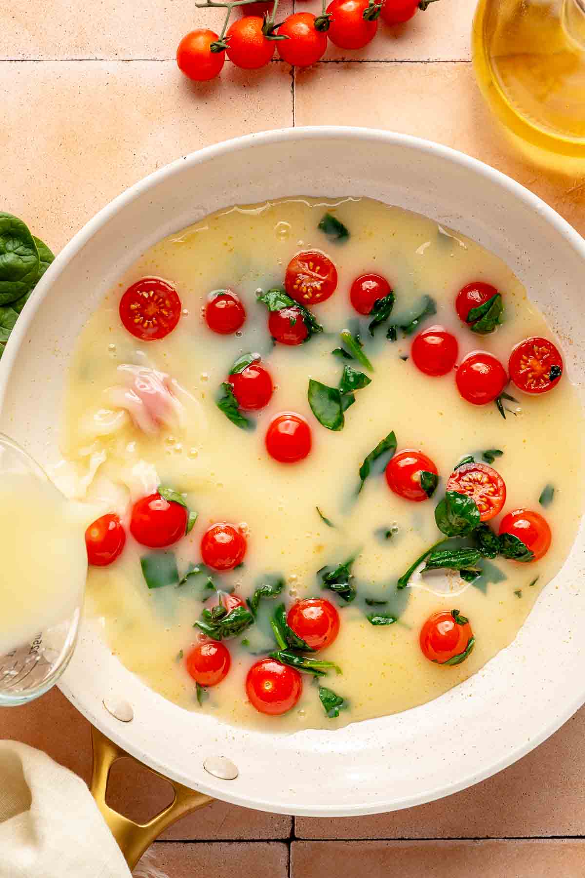 Adding egg whites to pan with cherry tomatoes and spinach.