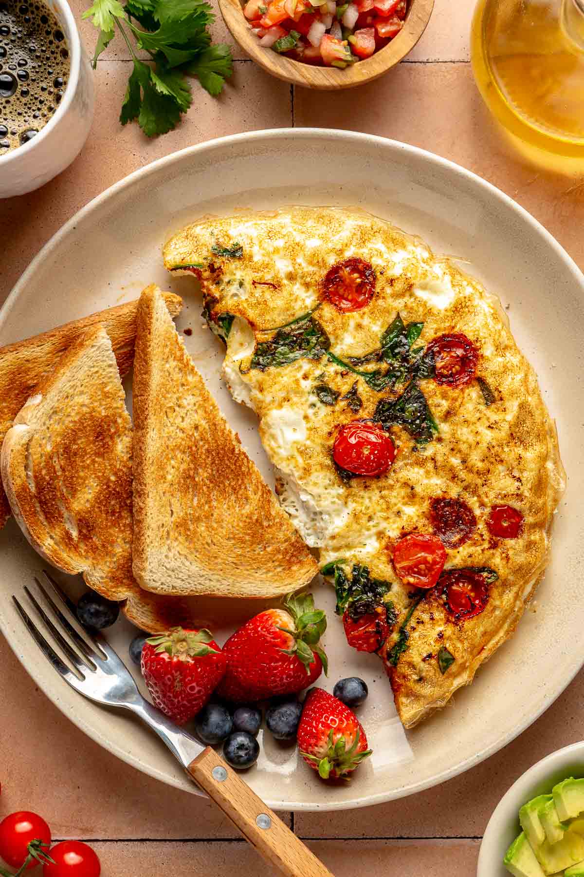 Omelet served with toast and fresh berries on a plate.