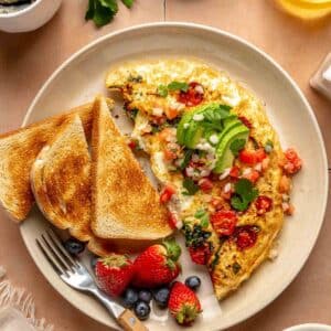 Omelet topped with avocado and cilantro.