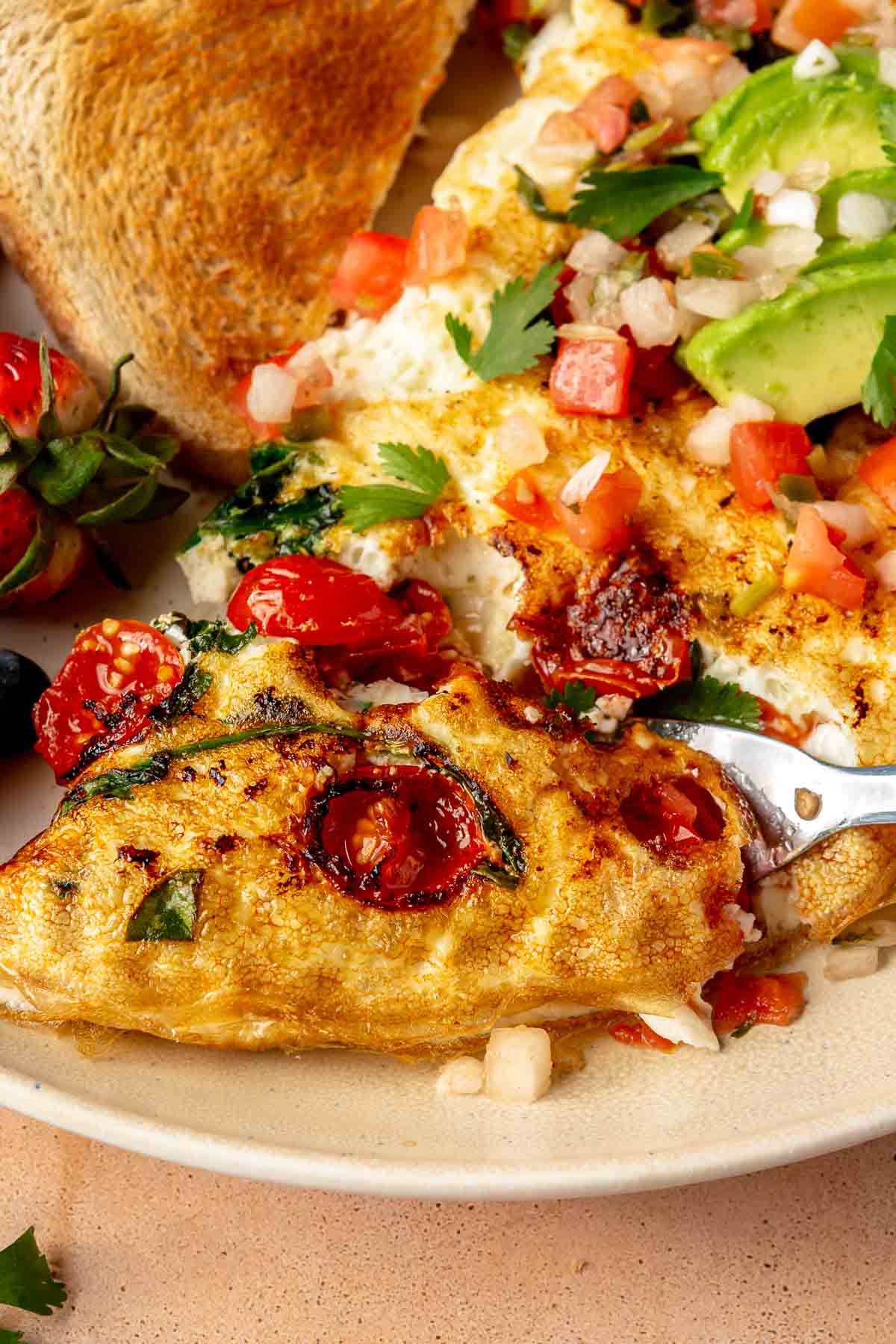 Using a fork to cut into an egg white omelet made with tomatoes.