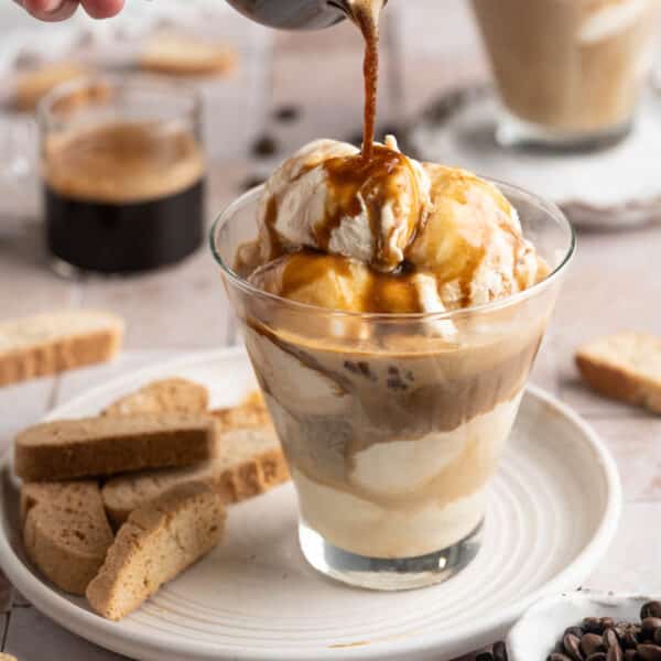 Pouring coffee over ice cream in a small glass.