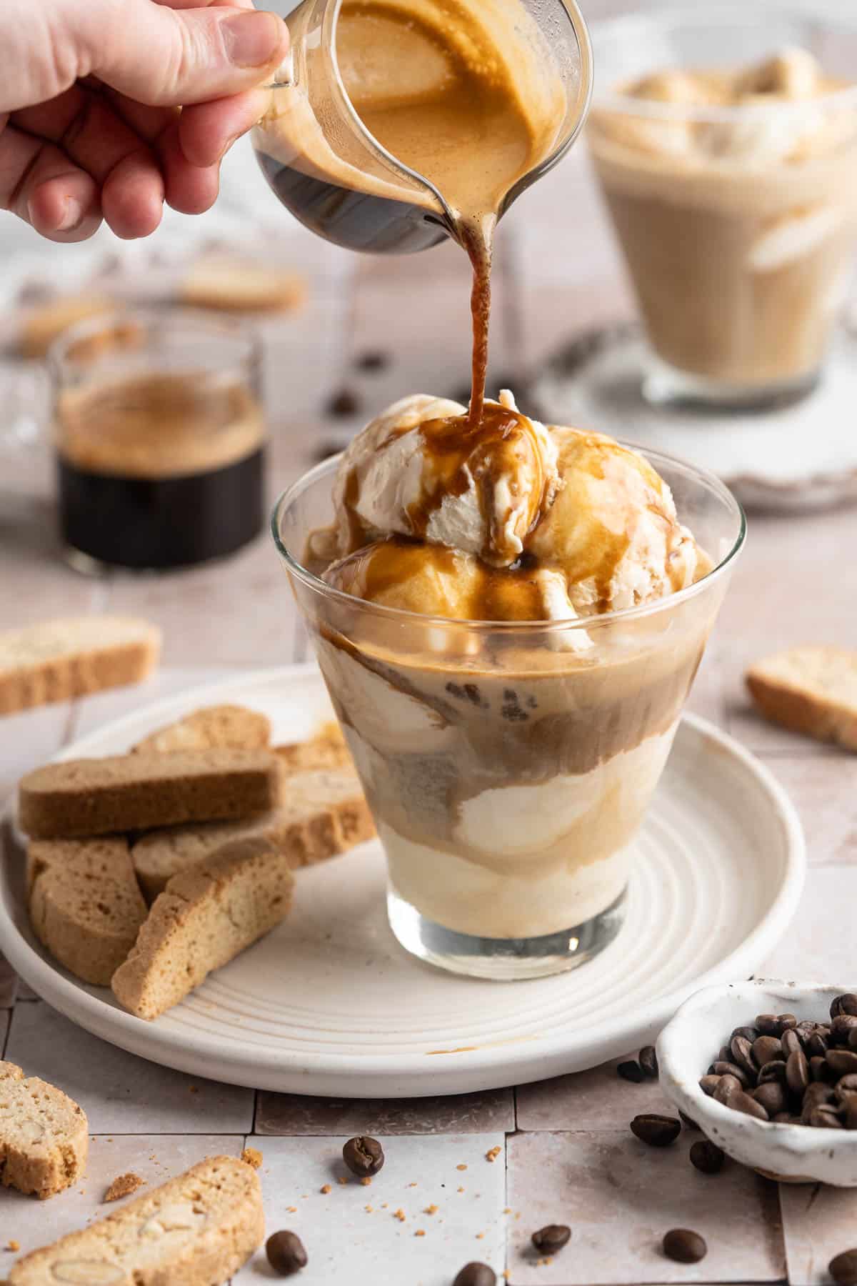 Pouring coffee over ice cream in a small glass.