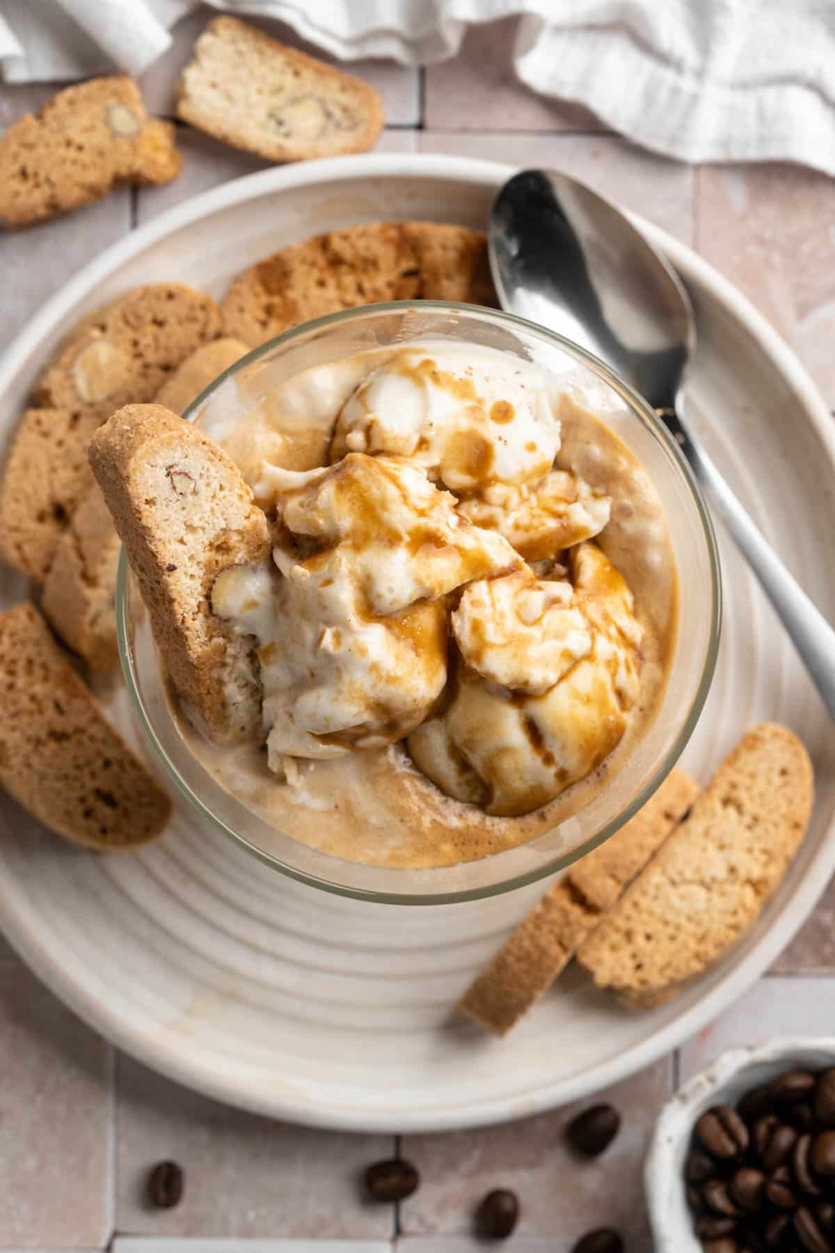 Salted caramel affogato in a glass served on a plate with biscotti.