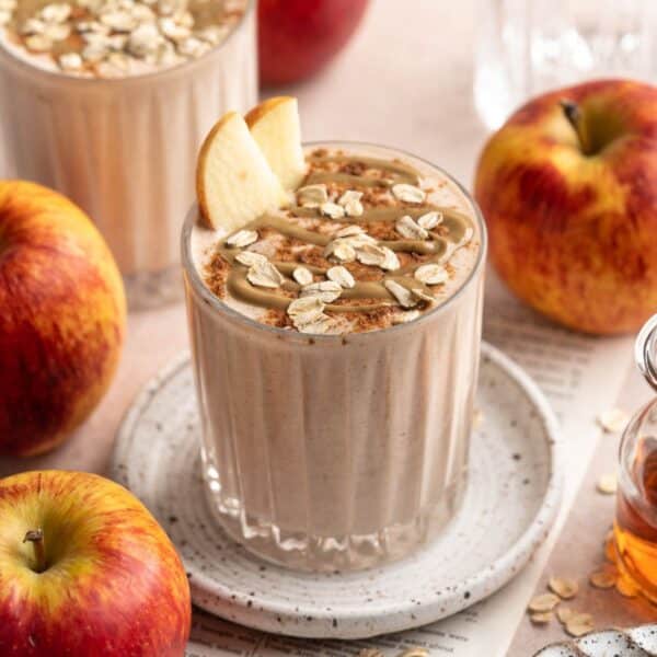 Apple smoothie topped with oats, a drizzle of peanut butter and apple slices.