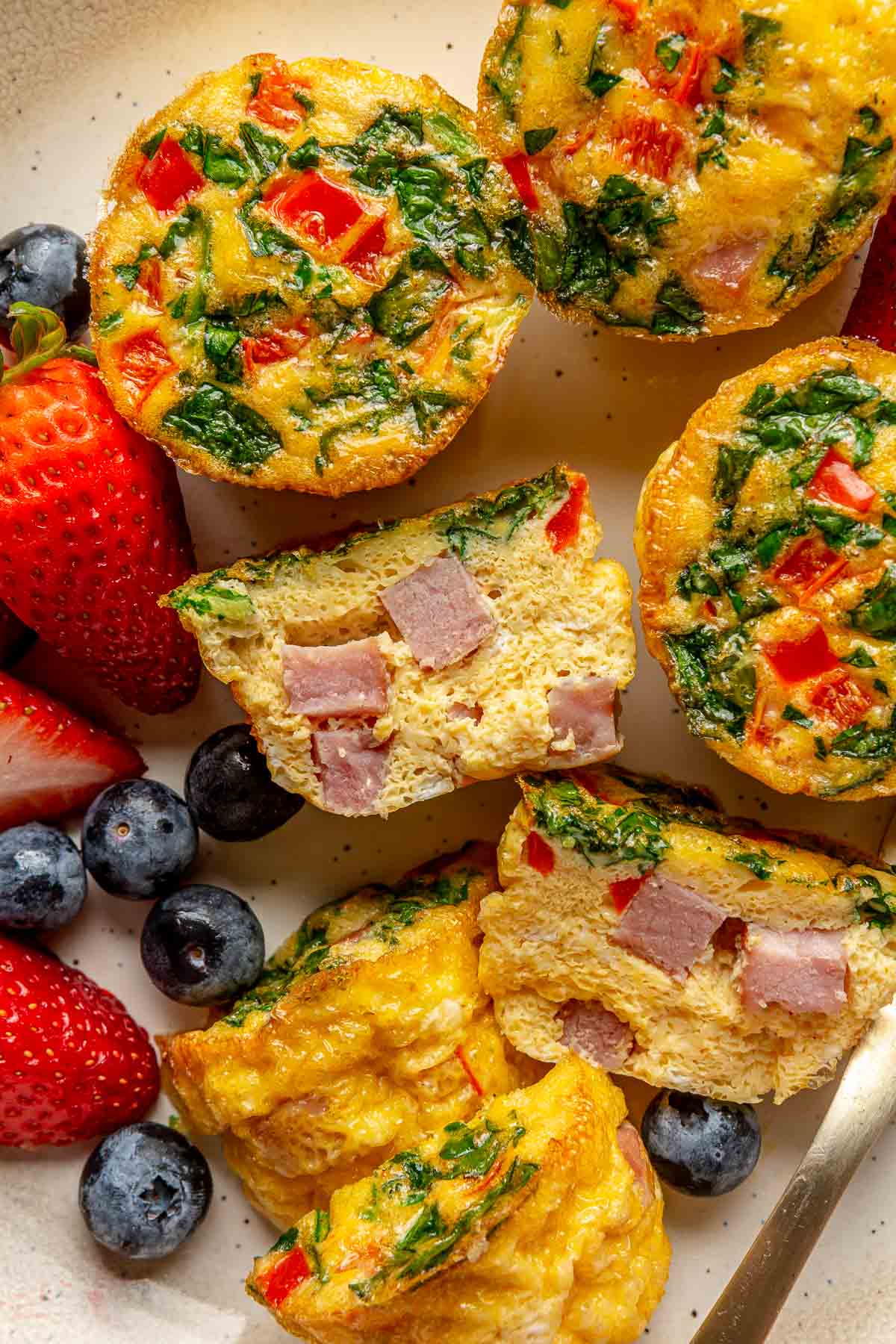 Egg muffins on a plate with one cut in half.