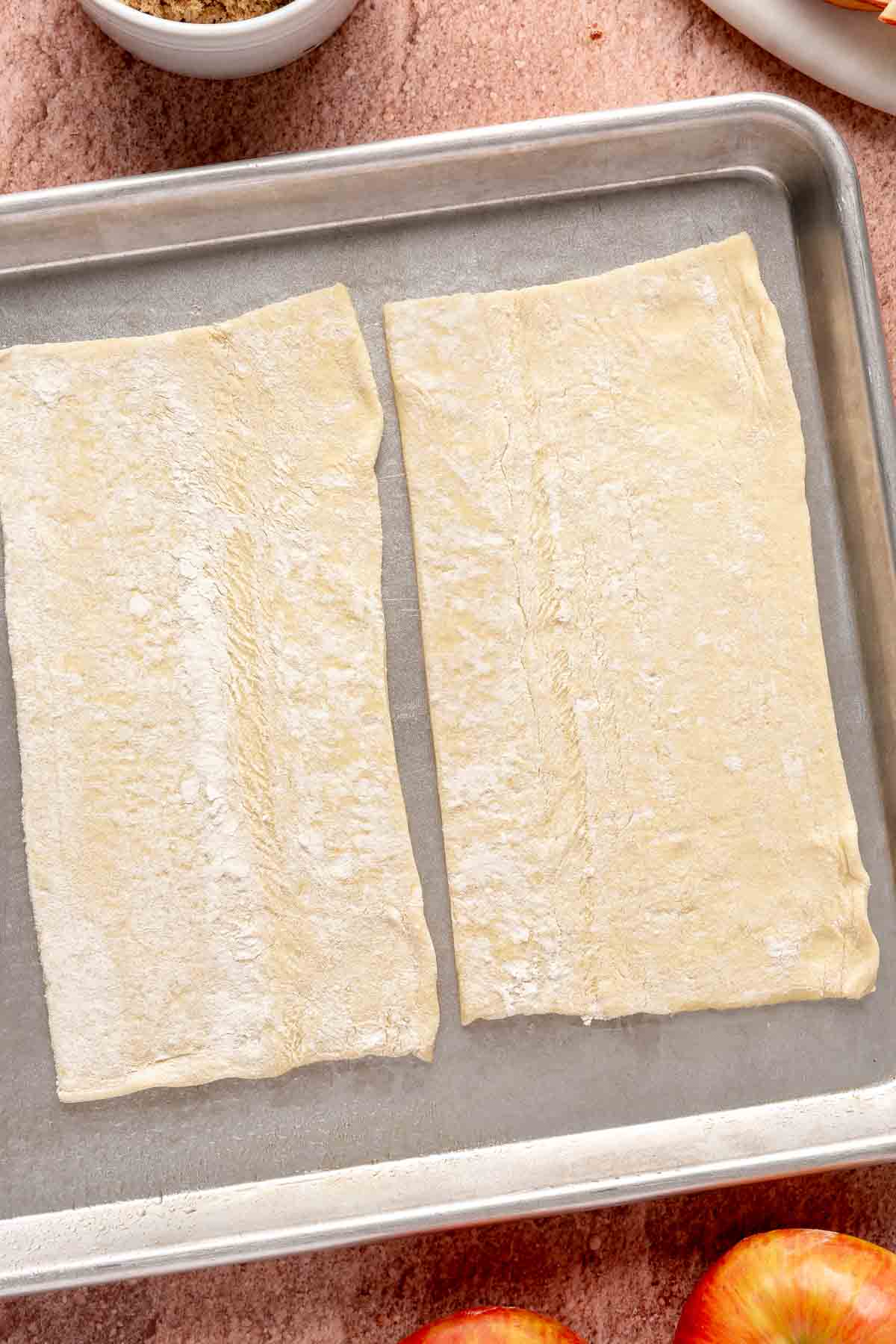 Puff pastry sheet cut in half on a baking sheet.