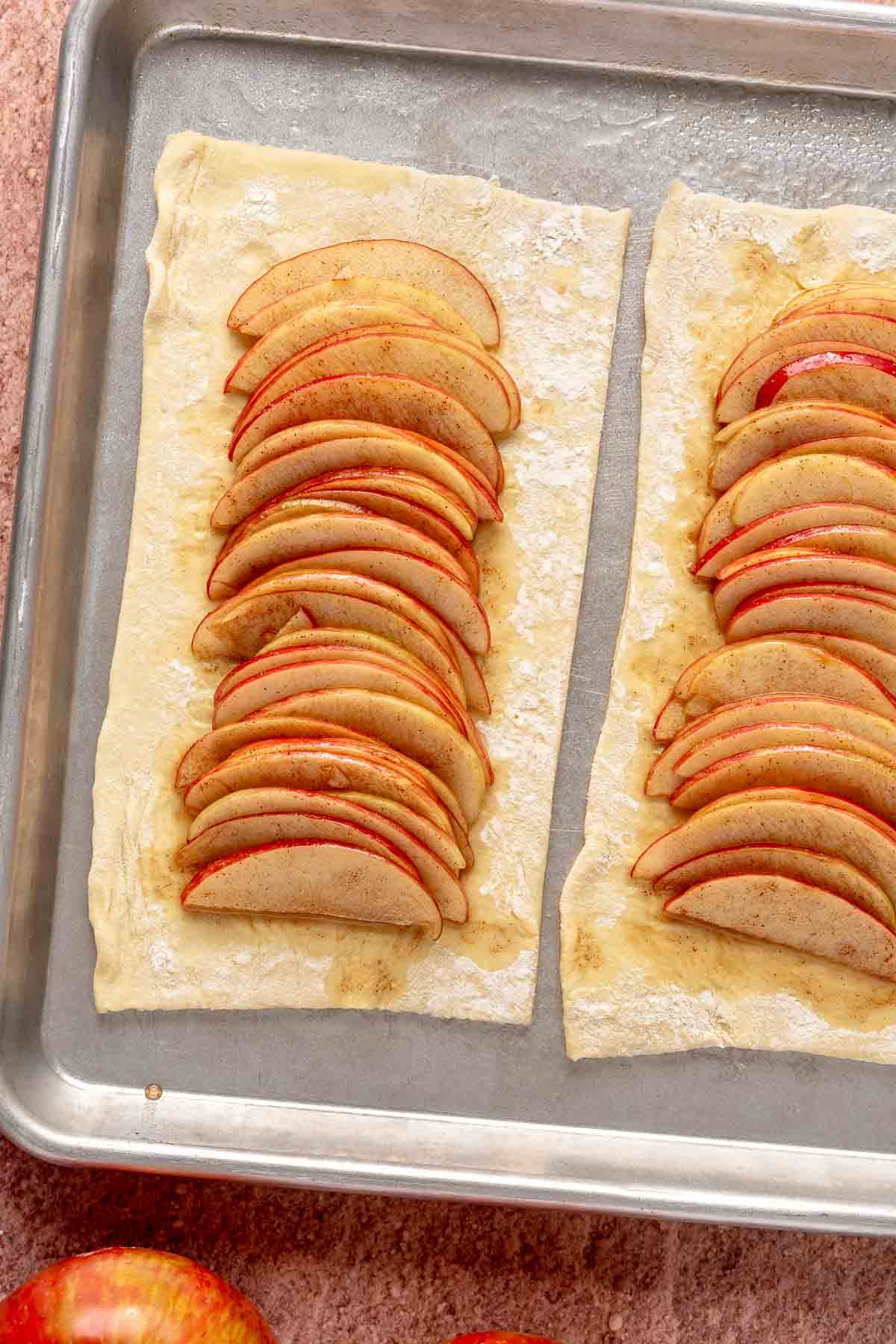 Apple slices layered in a row over puff pastry dough.