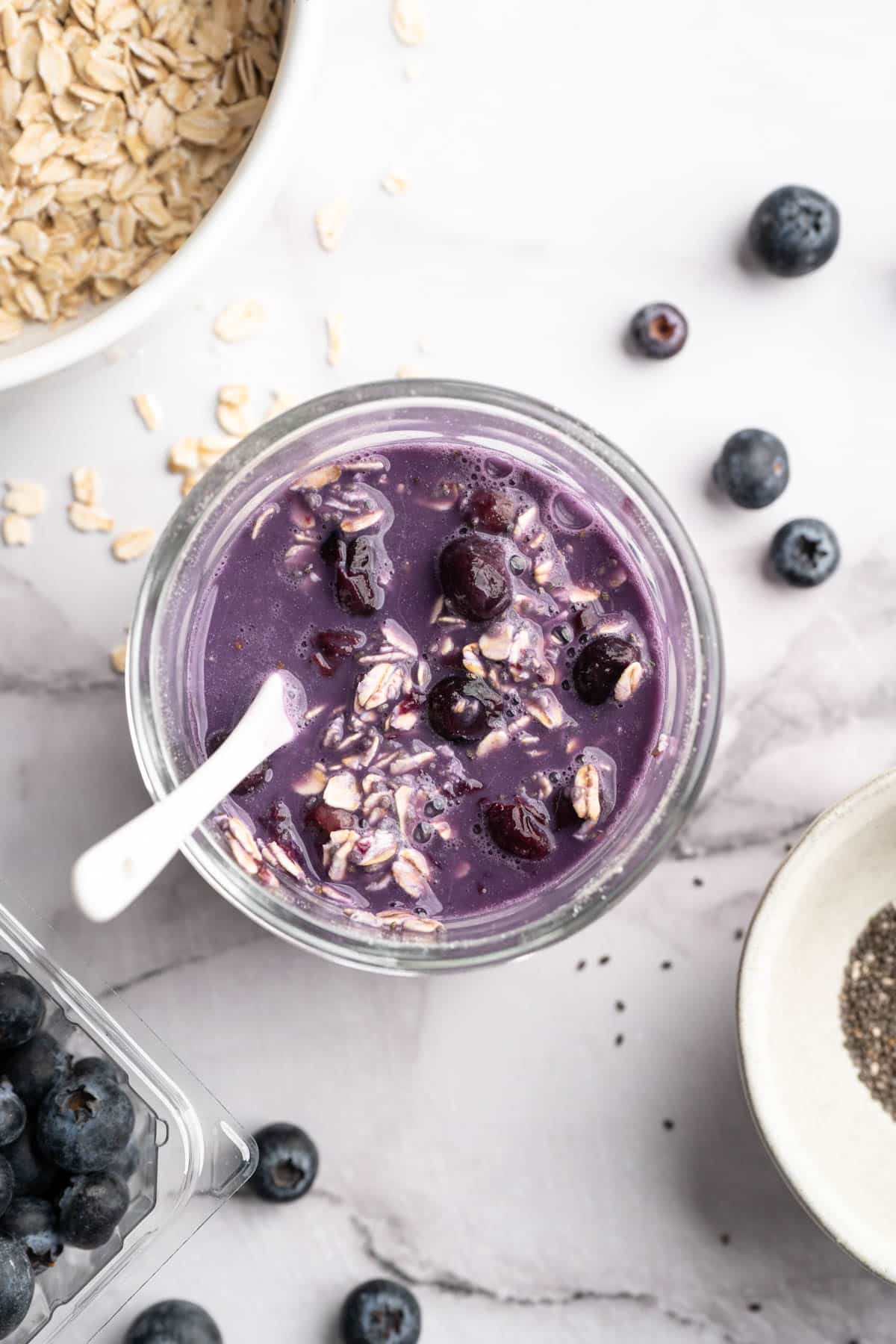 Stirring blueberry overnight oats in a small glass jar.