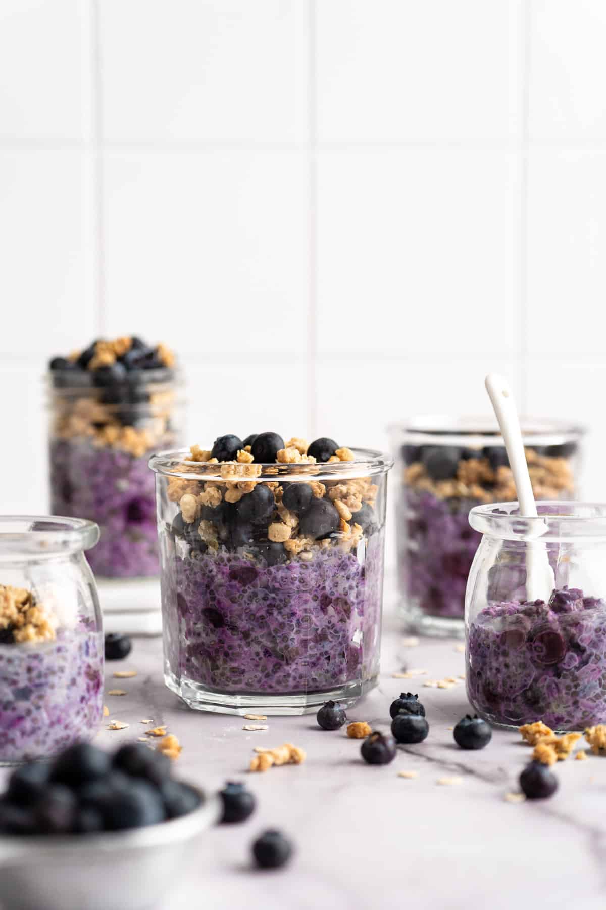 Blueberry Overnight Oatmeal in glass jars near fresh blueberries.