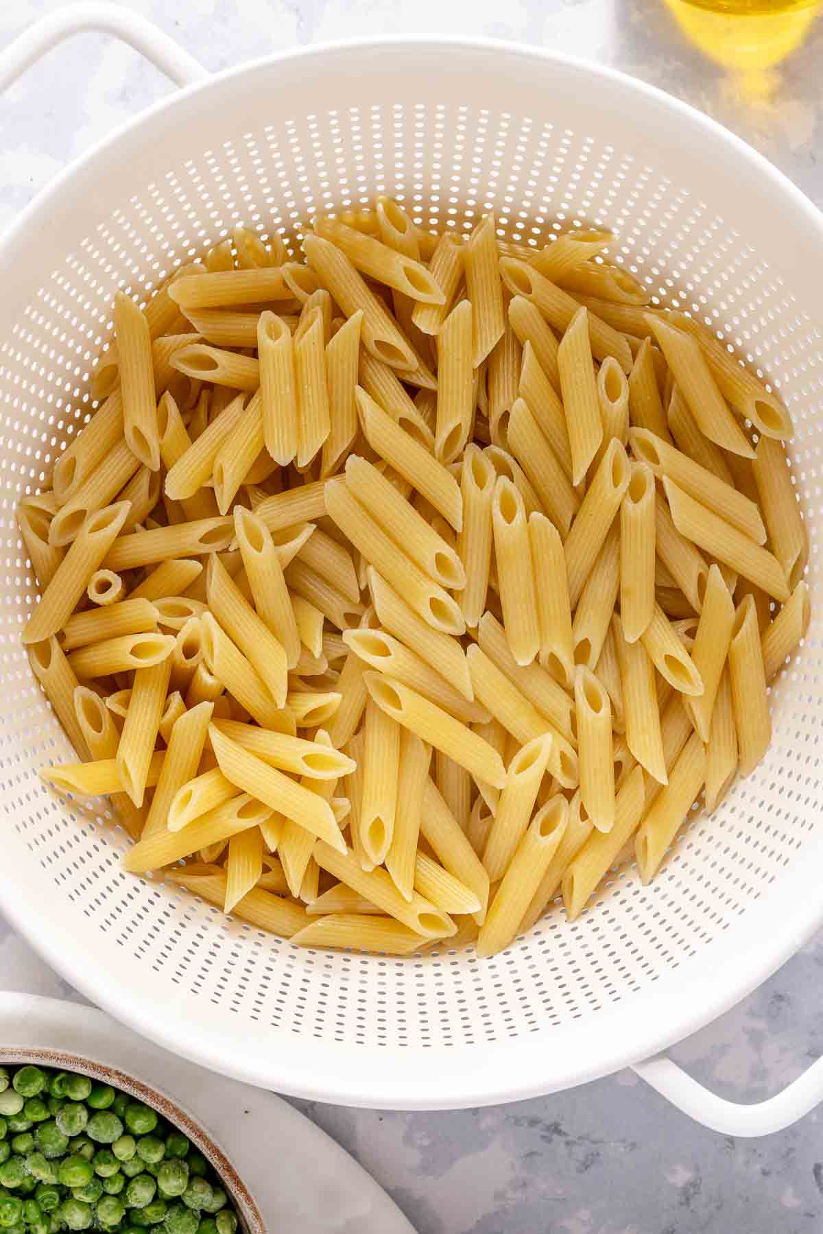 Drained penne pasta in a colander.