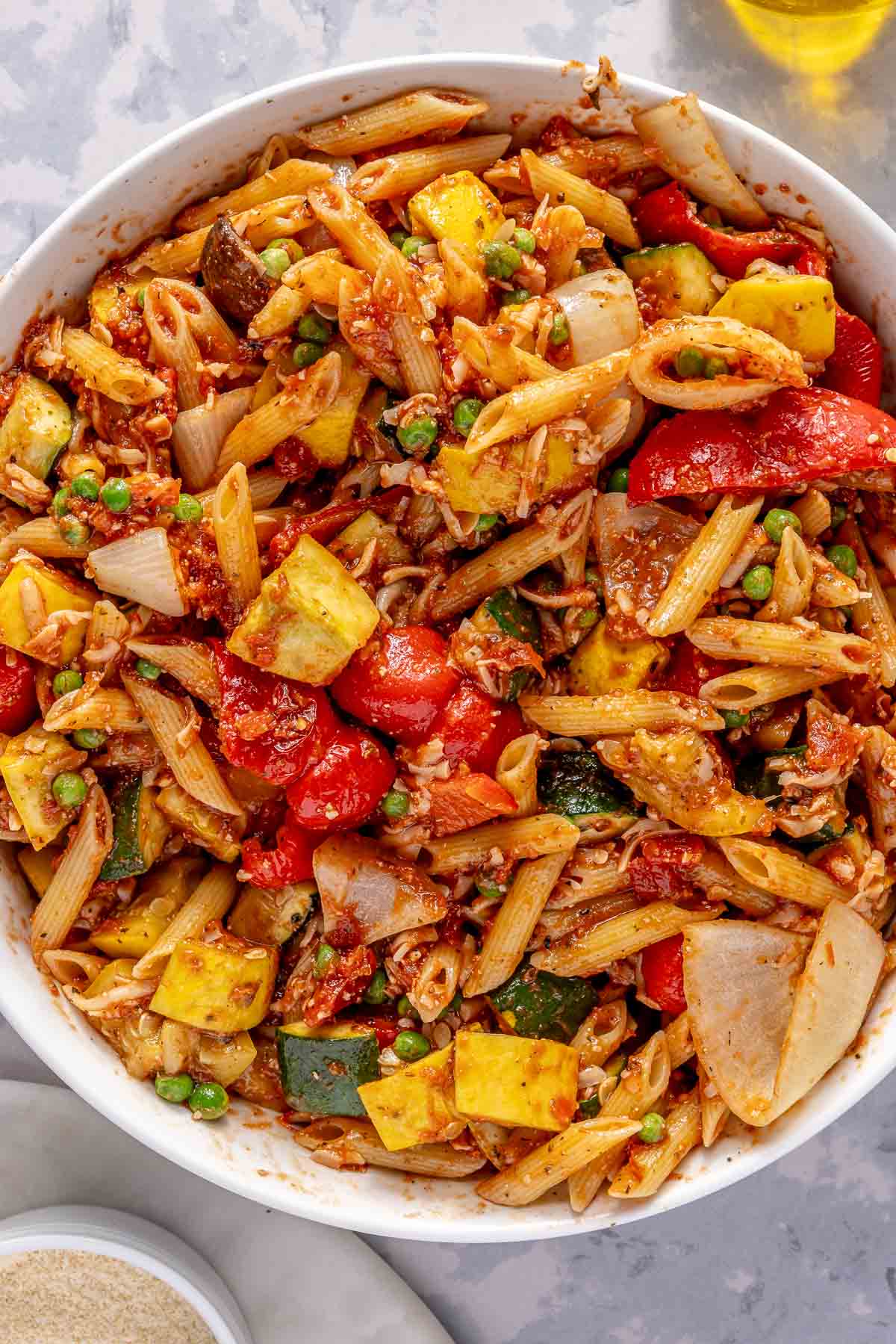 Roasted veggies mixed with pasta, cheese and marinara sauce in a large bowl.