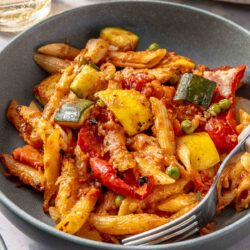 Vegetable pasta served in a bowl with a fork.