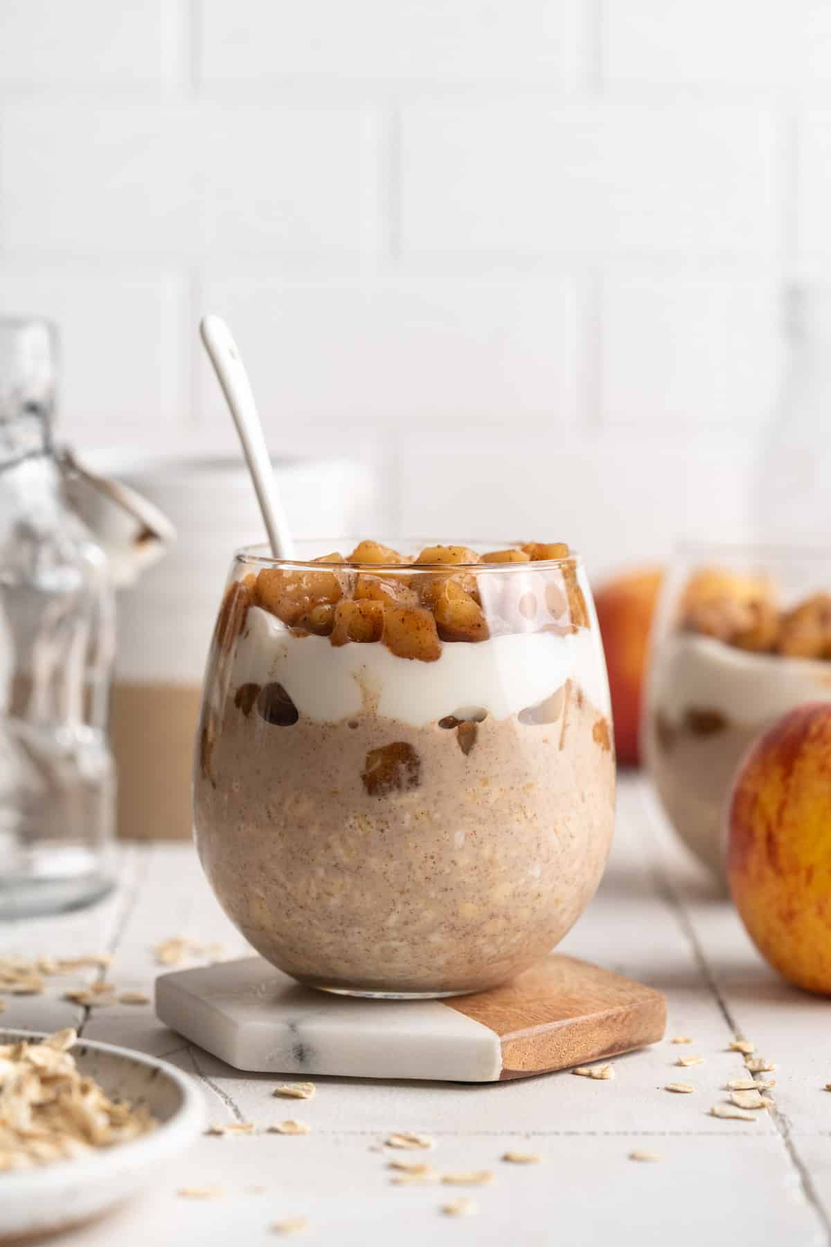 Layered apple cinnamon overnight oats in a glass with a spoon.