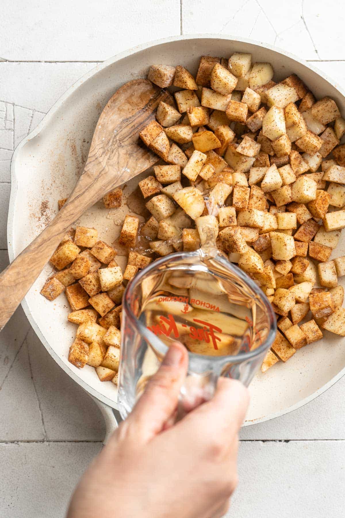 Pour water into skillet with diced apples and spices.