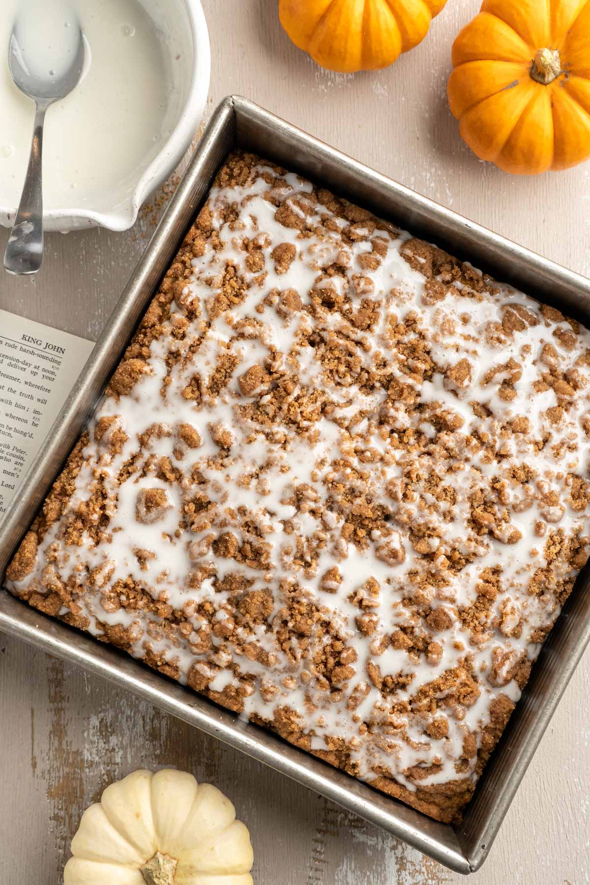 Pumpkin Coffee cake in pan drizzled with icing on top.