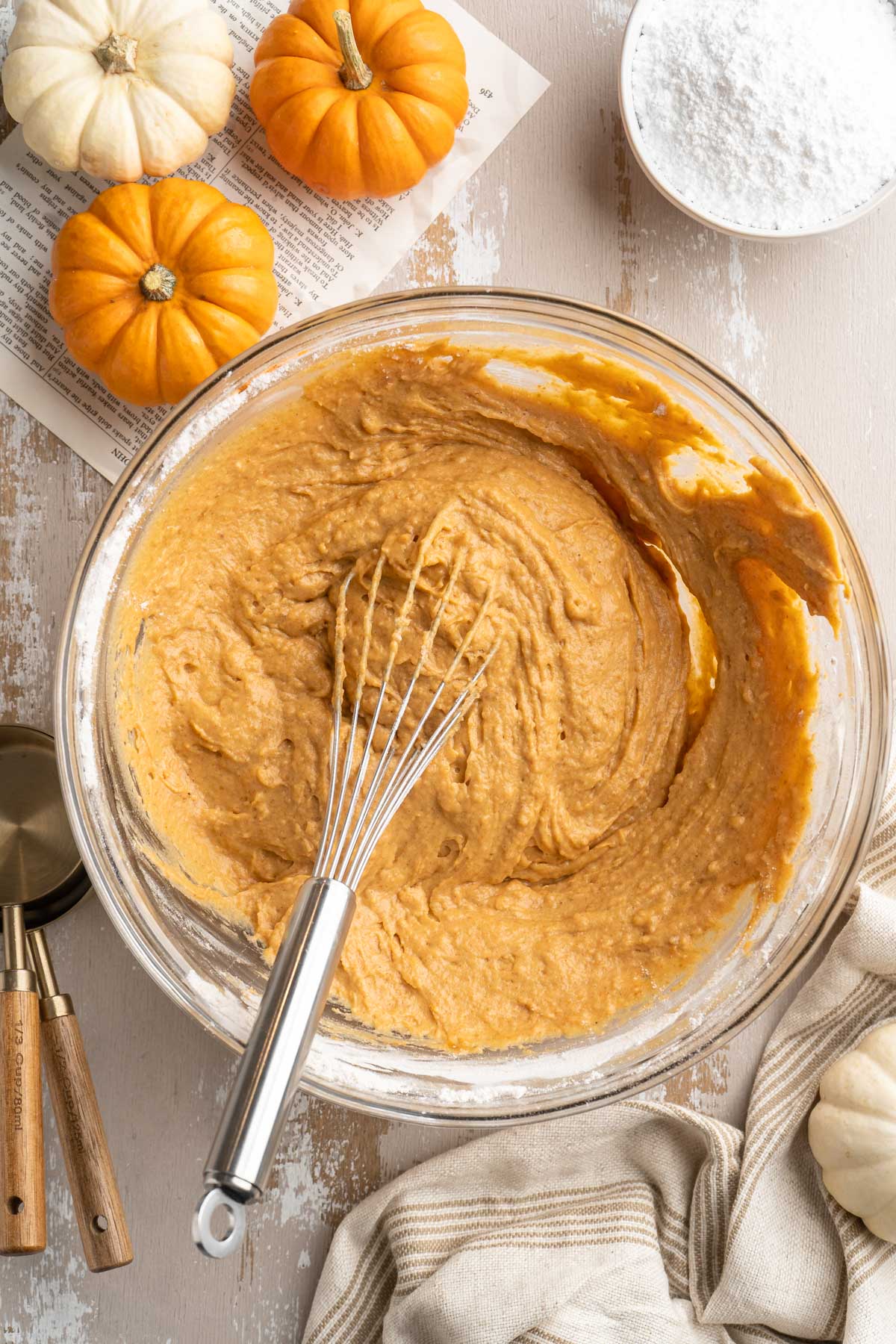 Stirring together wet pumpkin mixture with flour in a large glass mixing bowl.