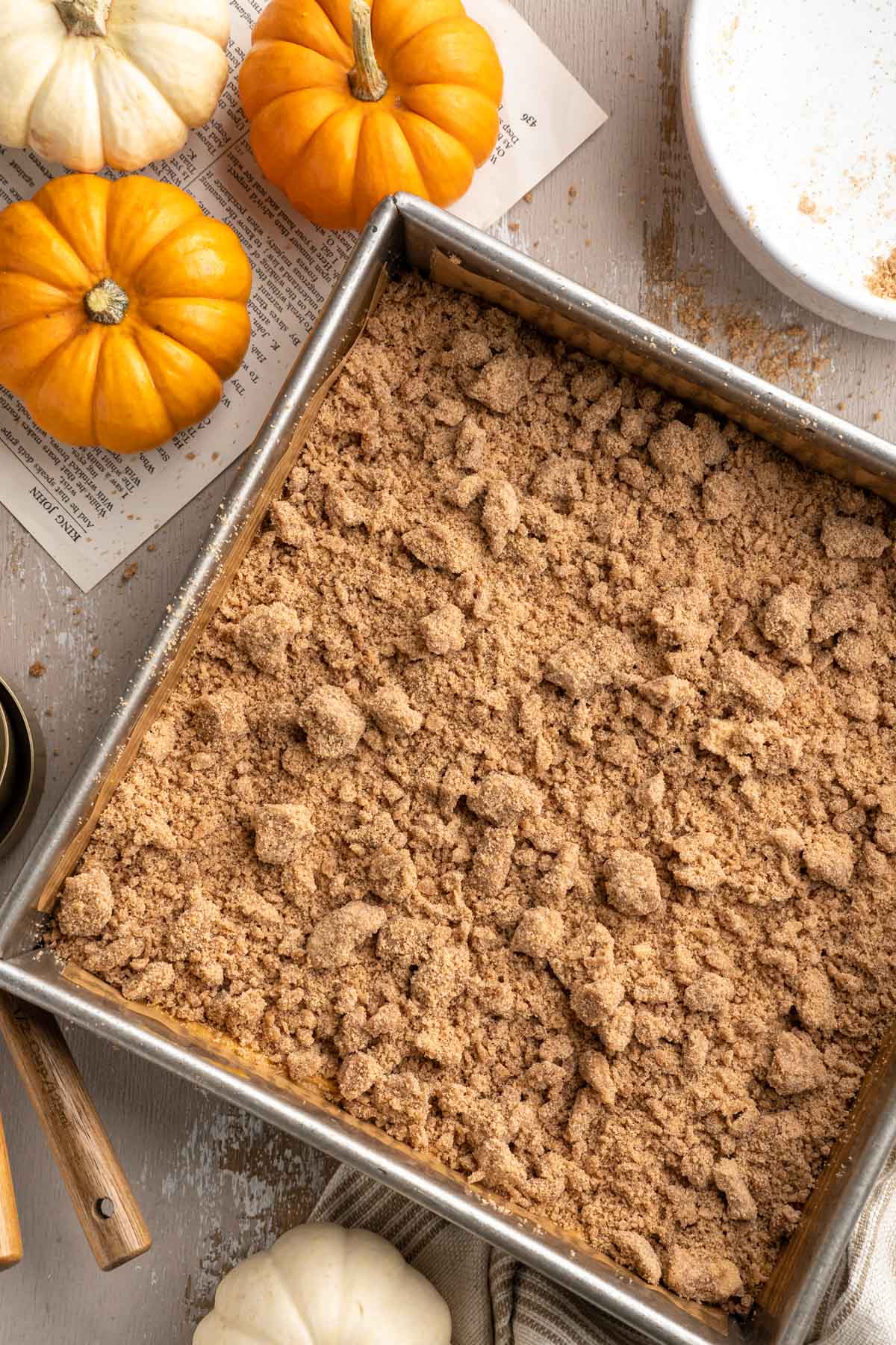 Cake in a square pan sprinkled with crumb topping before being baked.