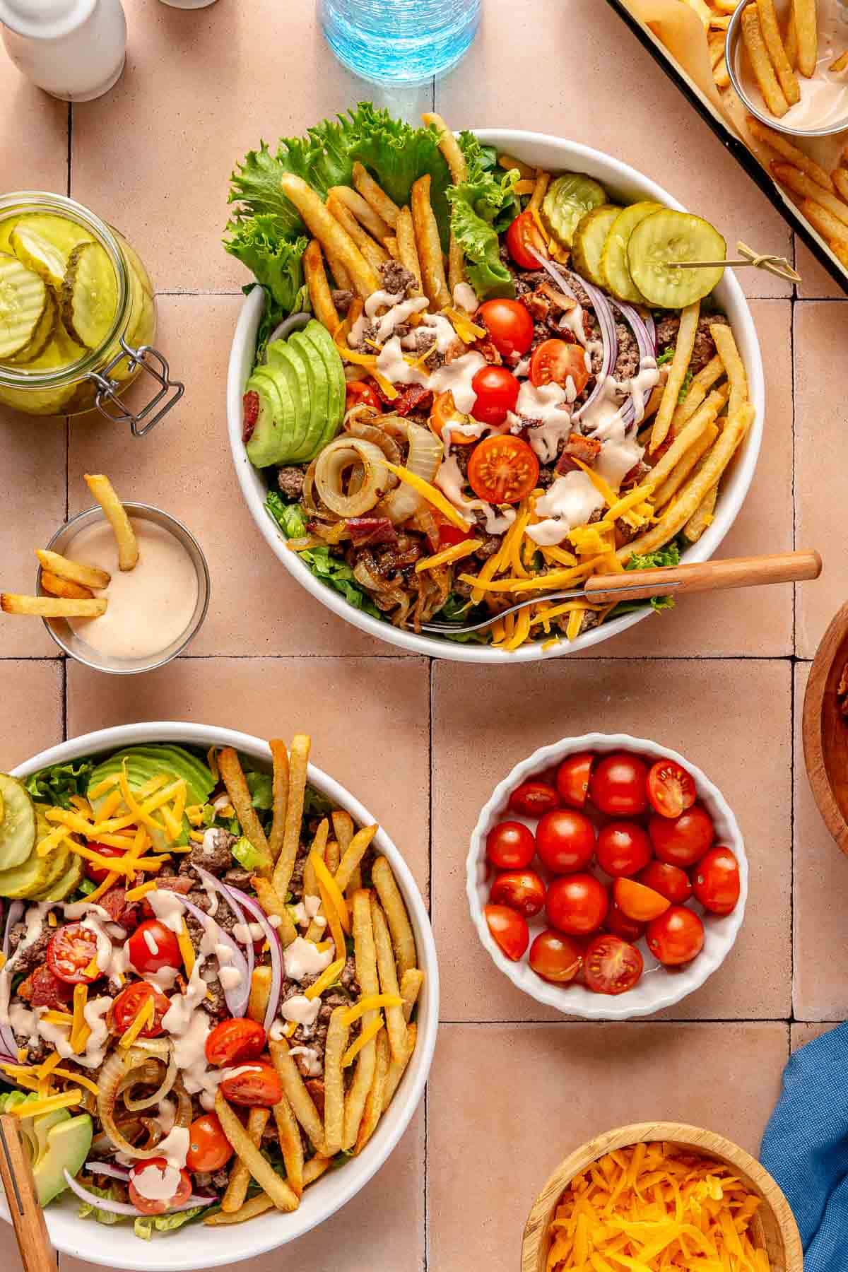 Hamburger bowls topped with French fries, pickles and burger sauce.