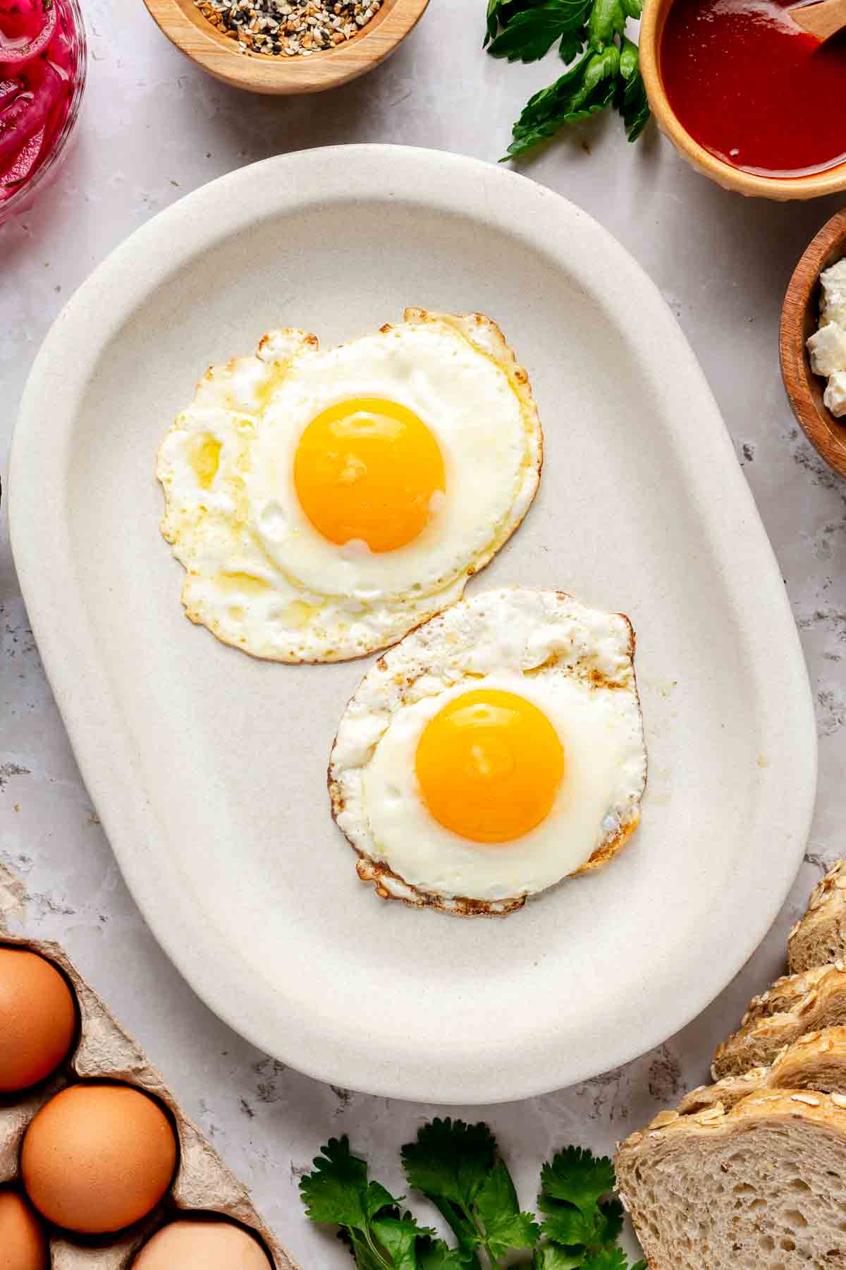 Two fried eggs on a white plate.