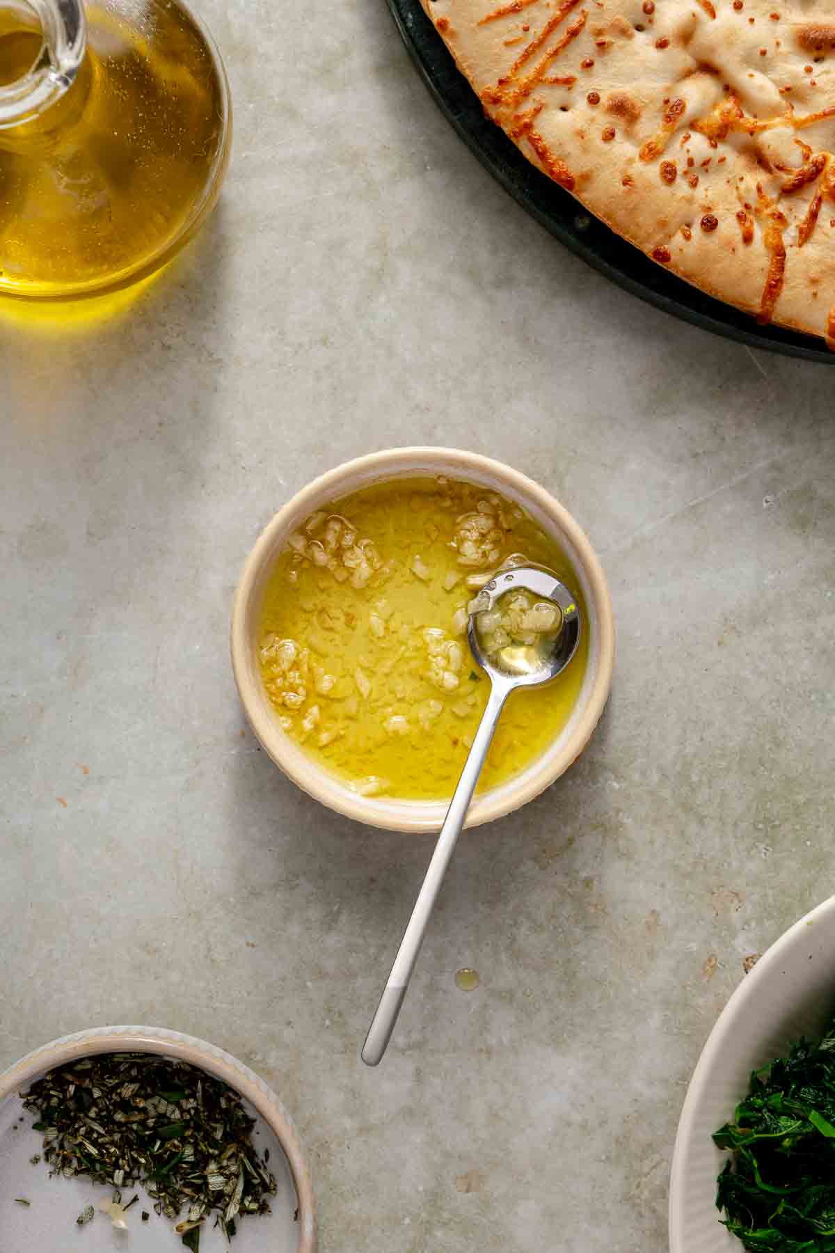 Stirring fresh garlic with olive oil in a small bowl.