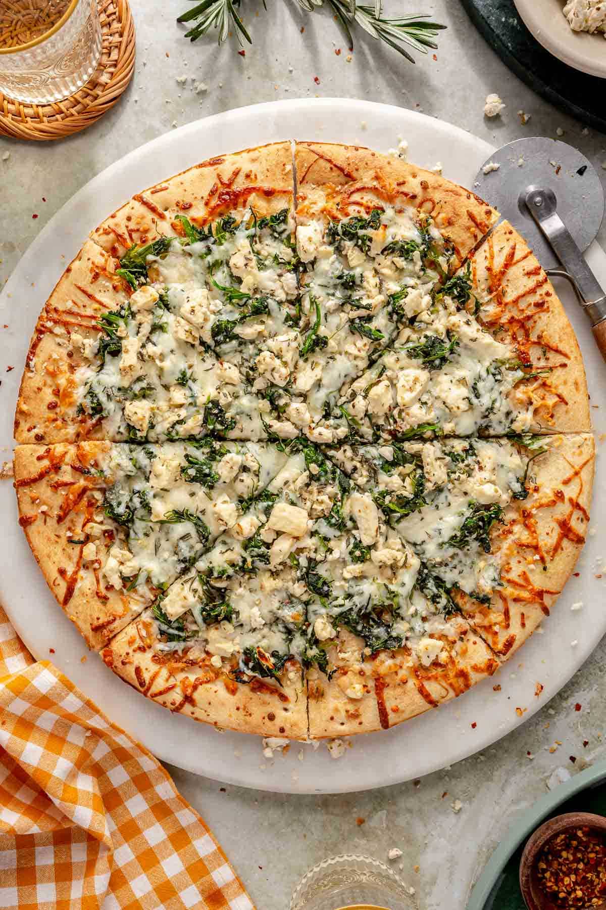 Baked white pizza sliced and on a large white pizza stone.