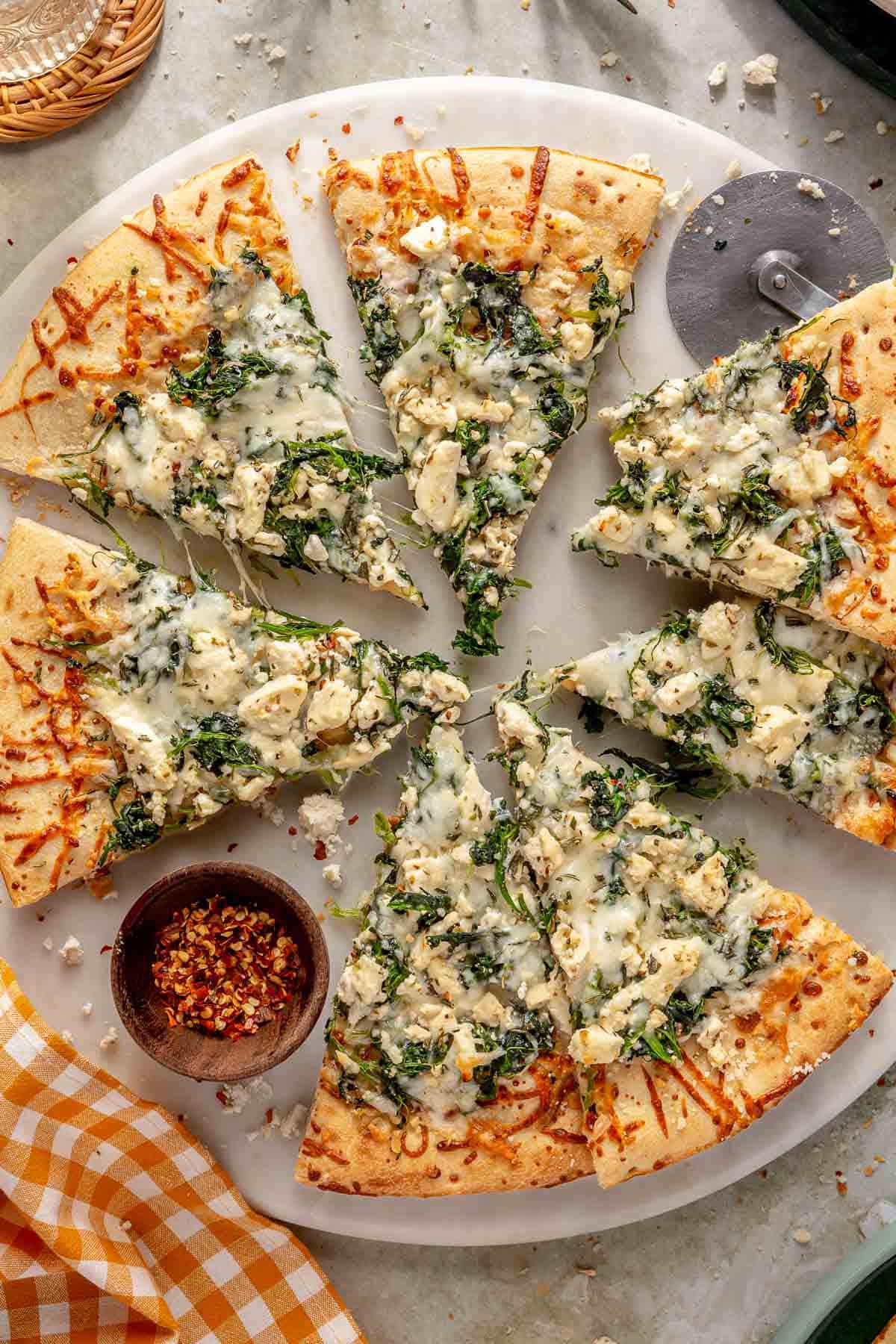 White pizza topped with spinach and mozzarella and cut into slices.